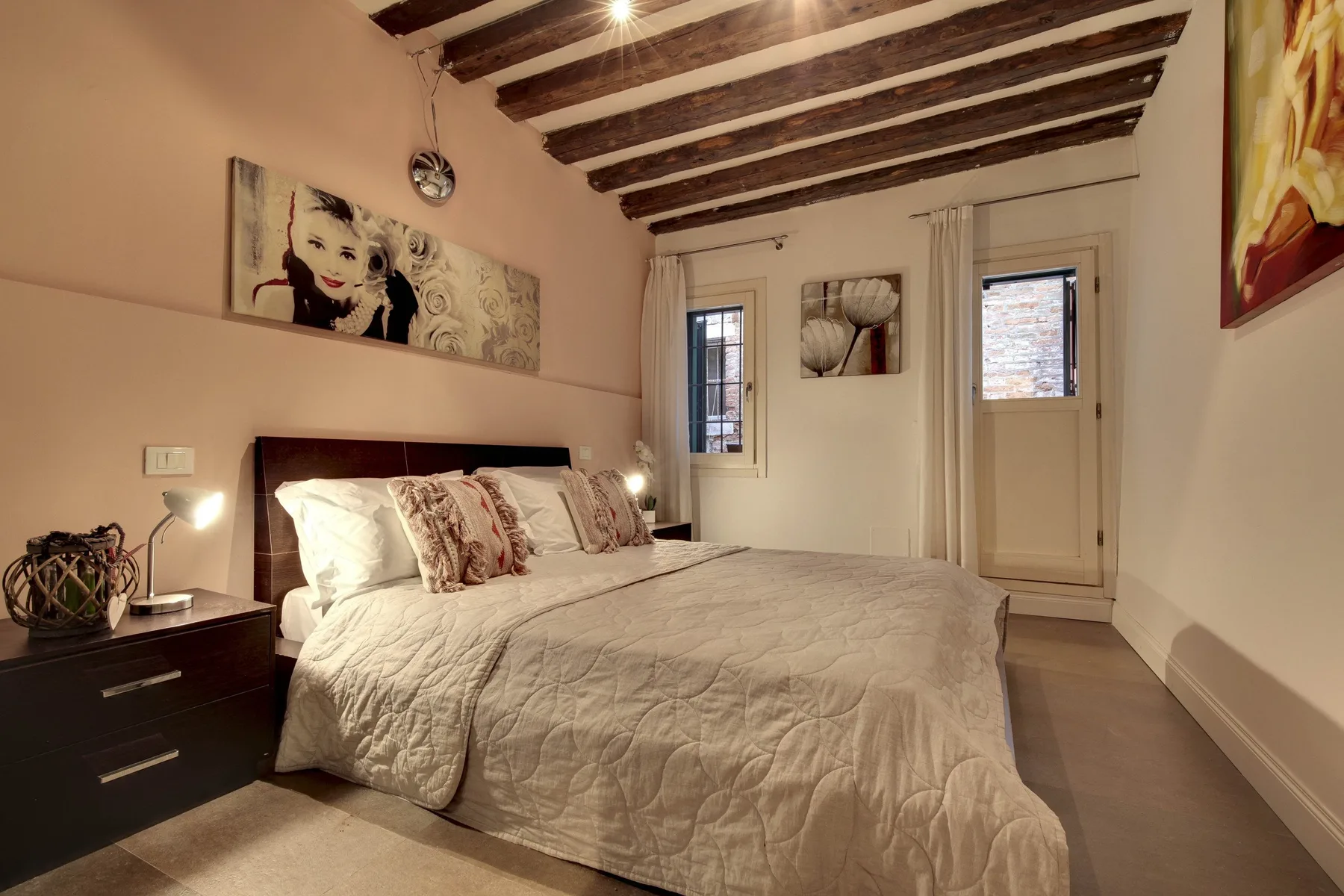 A bedroom with a large bed, bedside tables, and exposed ceiling beams.