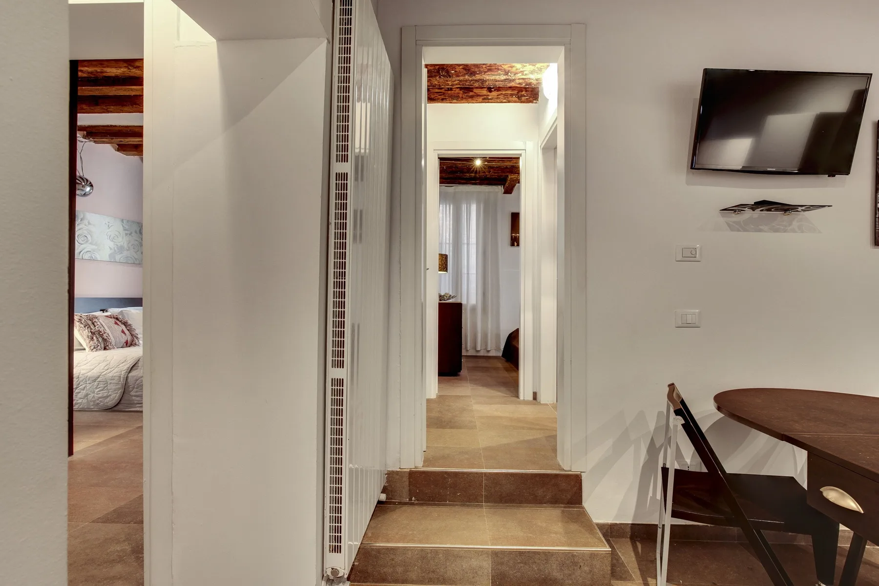 A bright interior hallway connects adjoining rooms, with a dining table beside the passage.