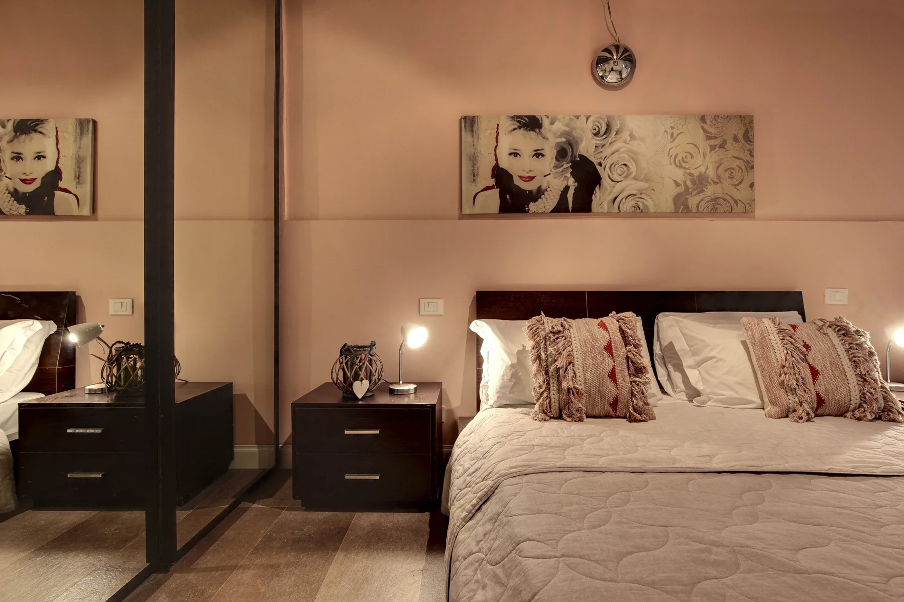 A bedroom with a large bed, bedside tables, and framed artwork above the bed.