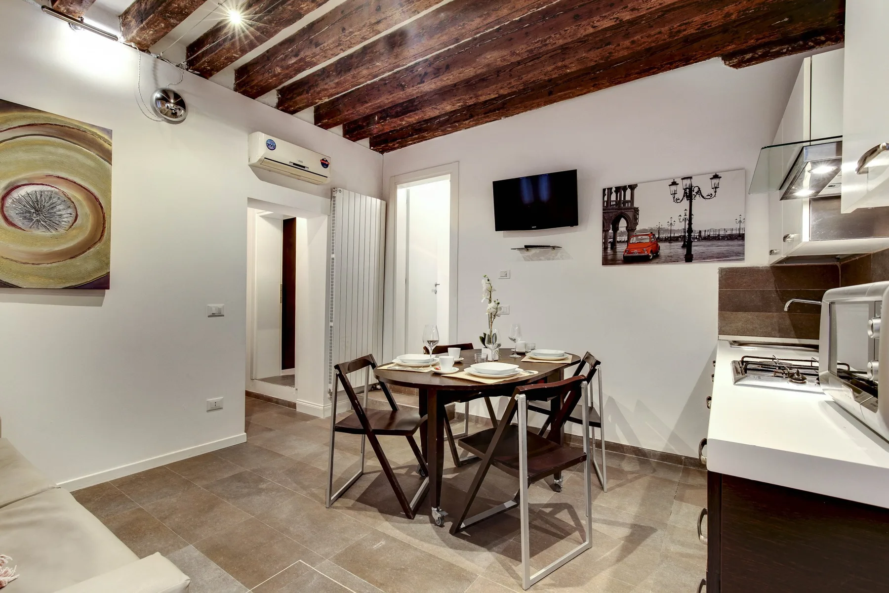 A dining area with a table and chairs beside a compact kitchen.