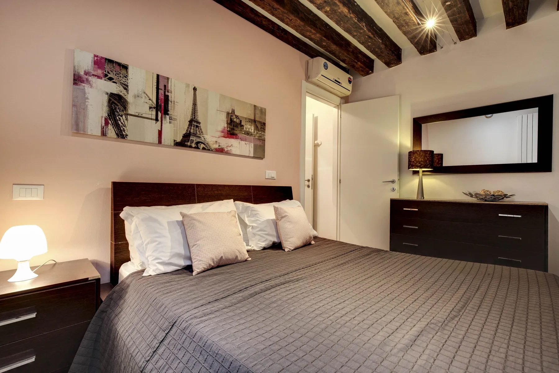 A bedroom with a neatly made bed and framed wall art.