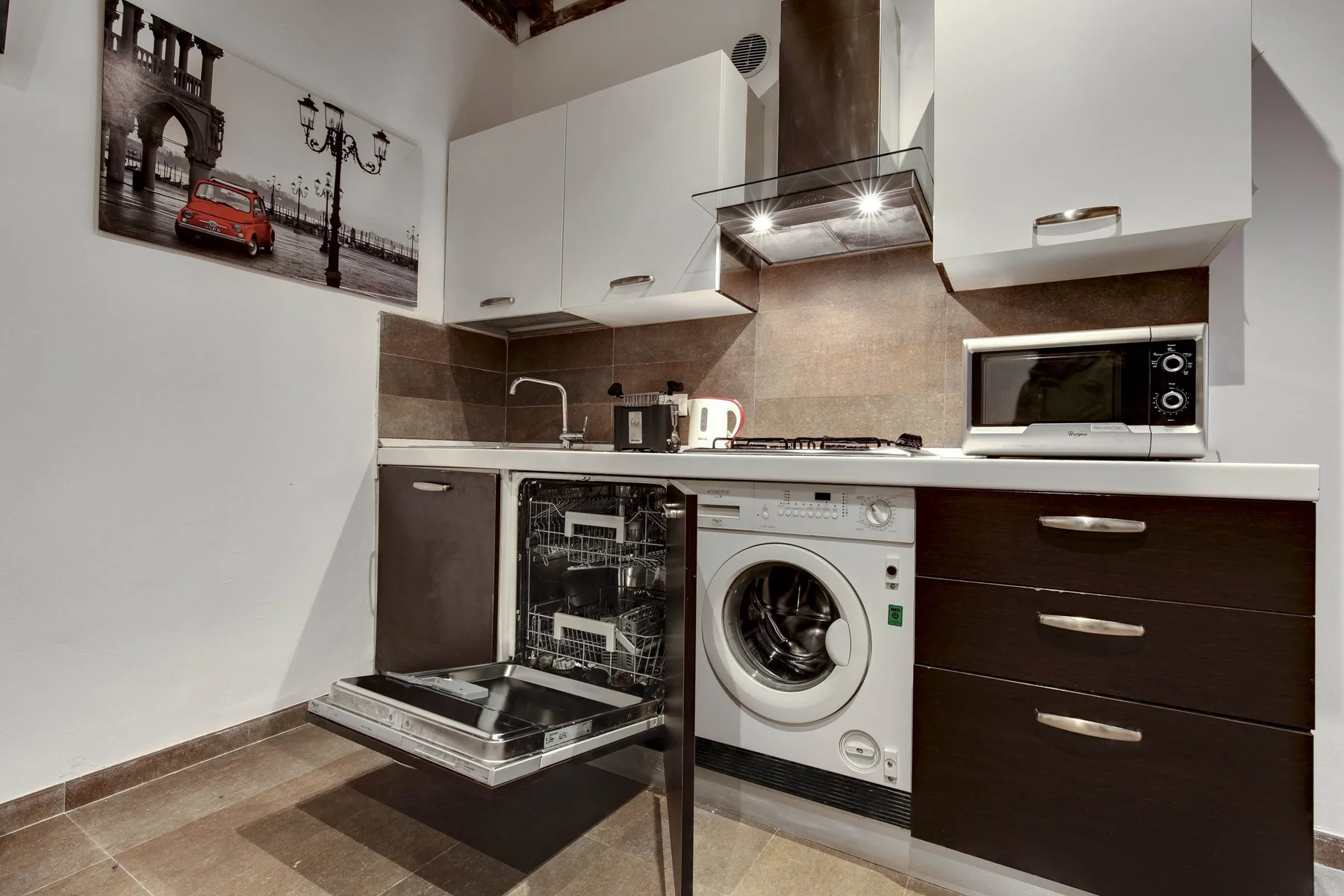 A compact kitchen with a built-in oven, washing machine, and countertop appliances.