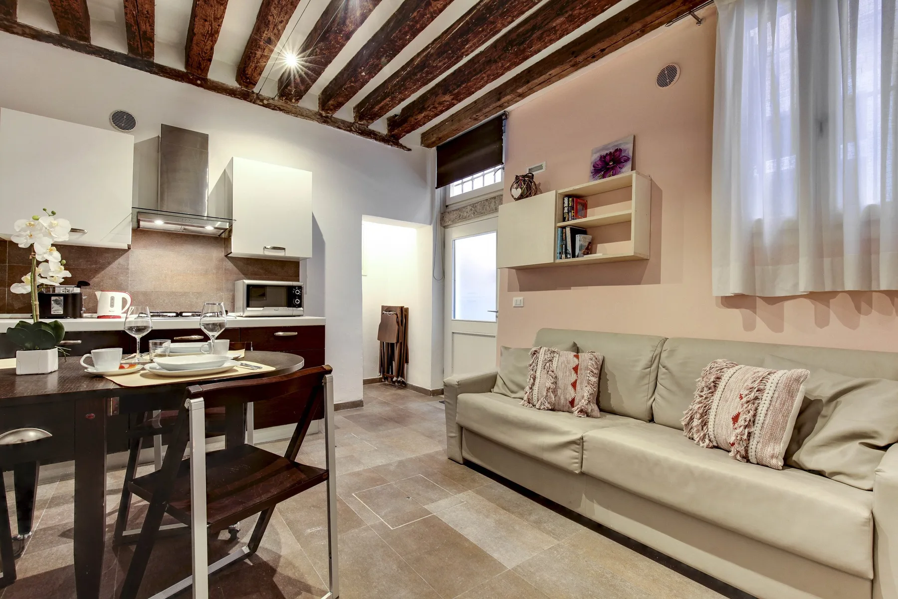 A living room with a sofa beside a compact kitchen and dining table.
