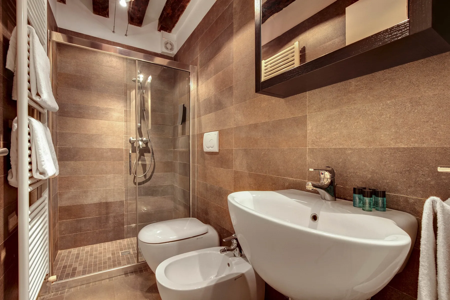 A tiled bathroom with a bathtub, shower, and wall-mounted towel rack.