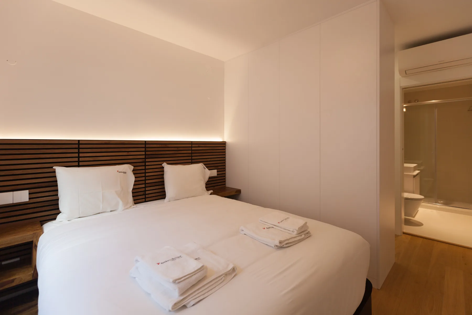 Dormitorio con una cama bien tendida y toallas dobladas.