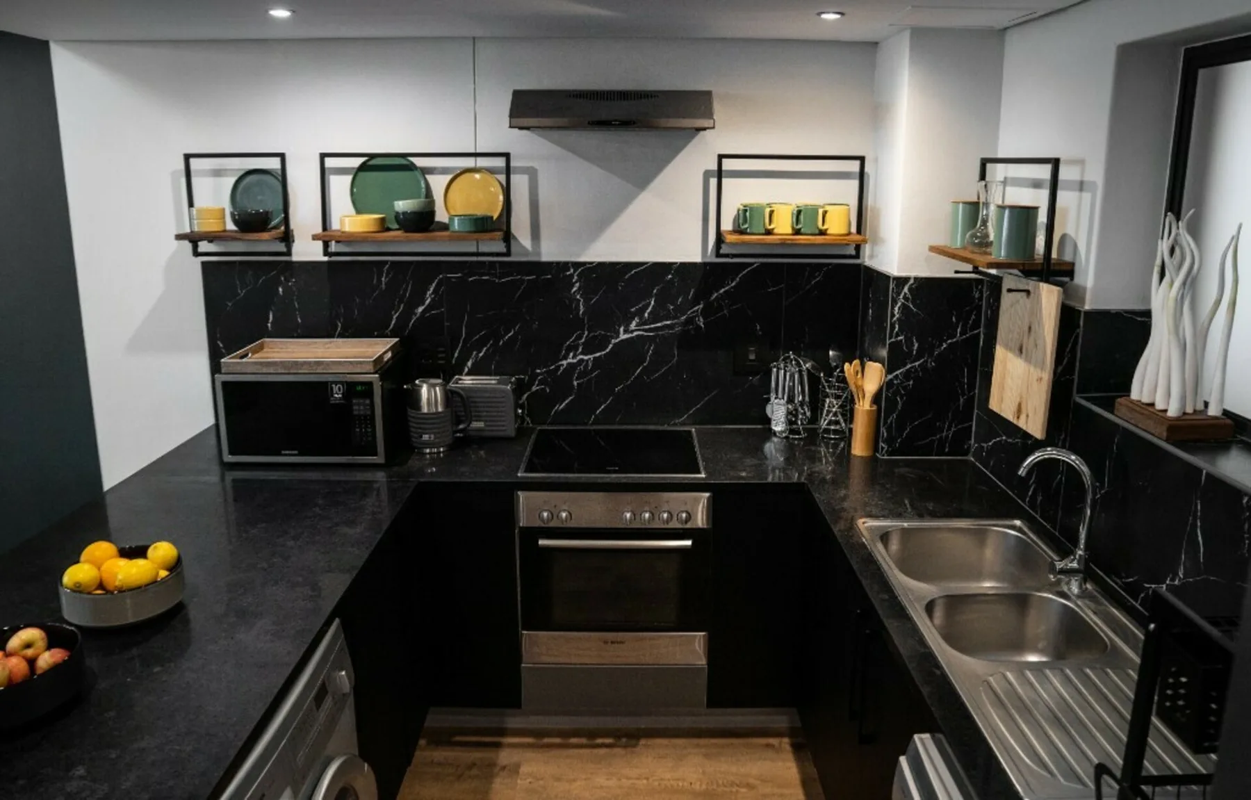 Modern kitchen with dark countertops, a built-in oven, and a double sink.