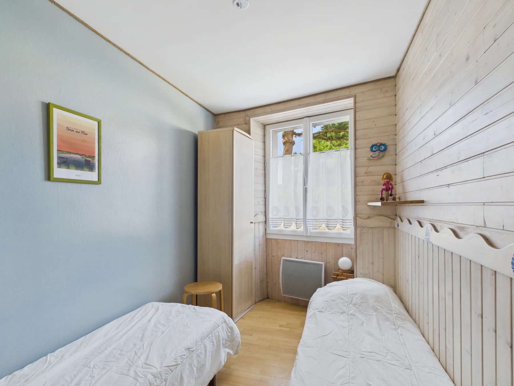 A small bedroom with two beds and a window.