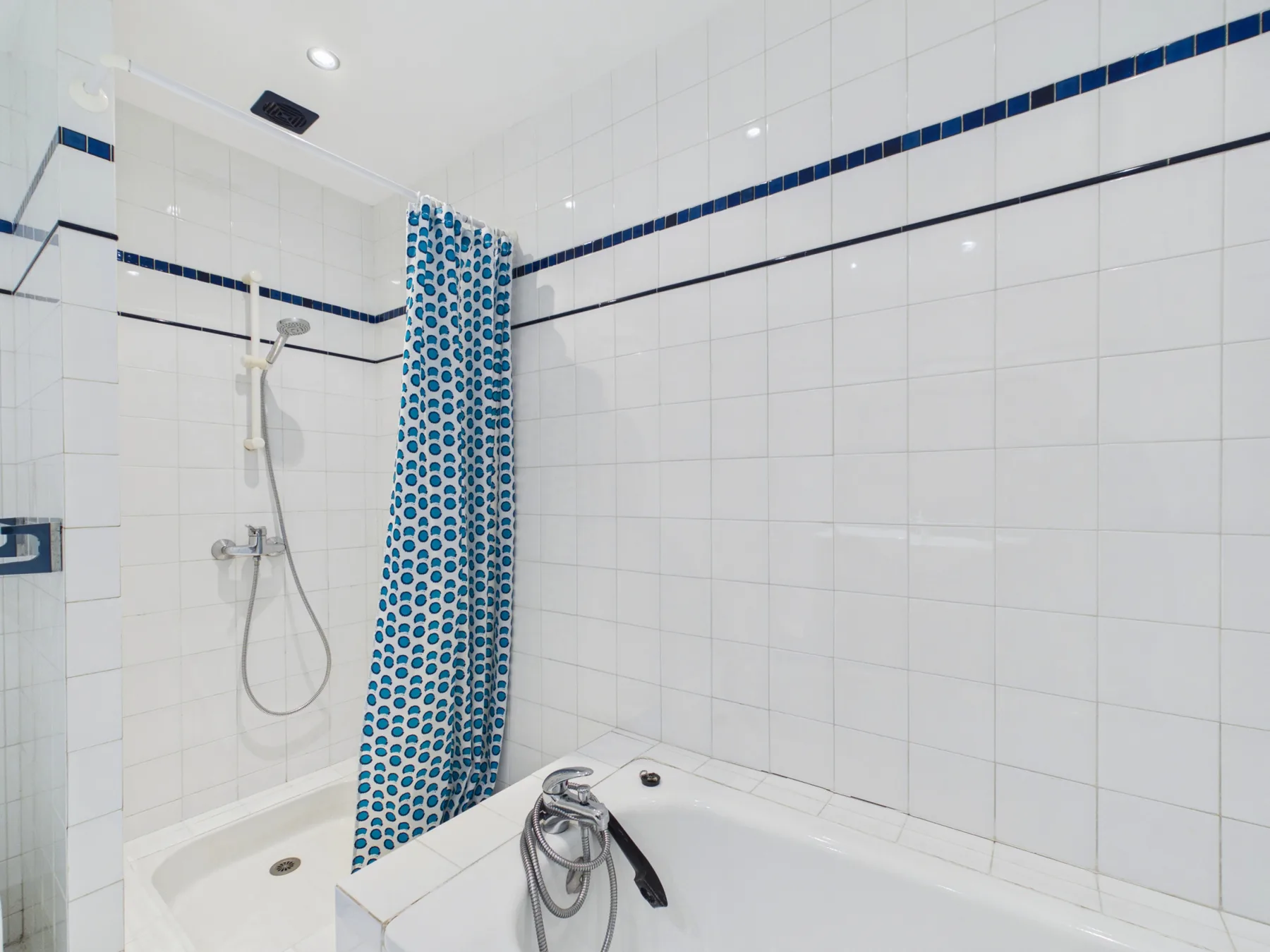 A tiled bathroom with a bathtub and patterned shower curtain.