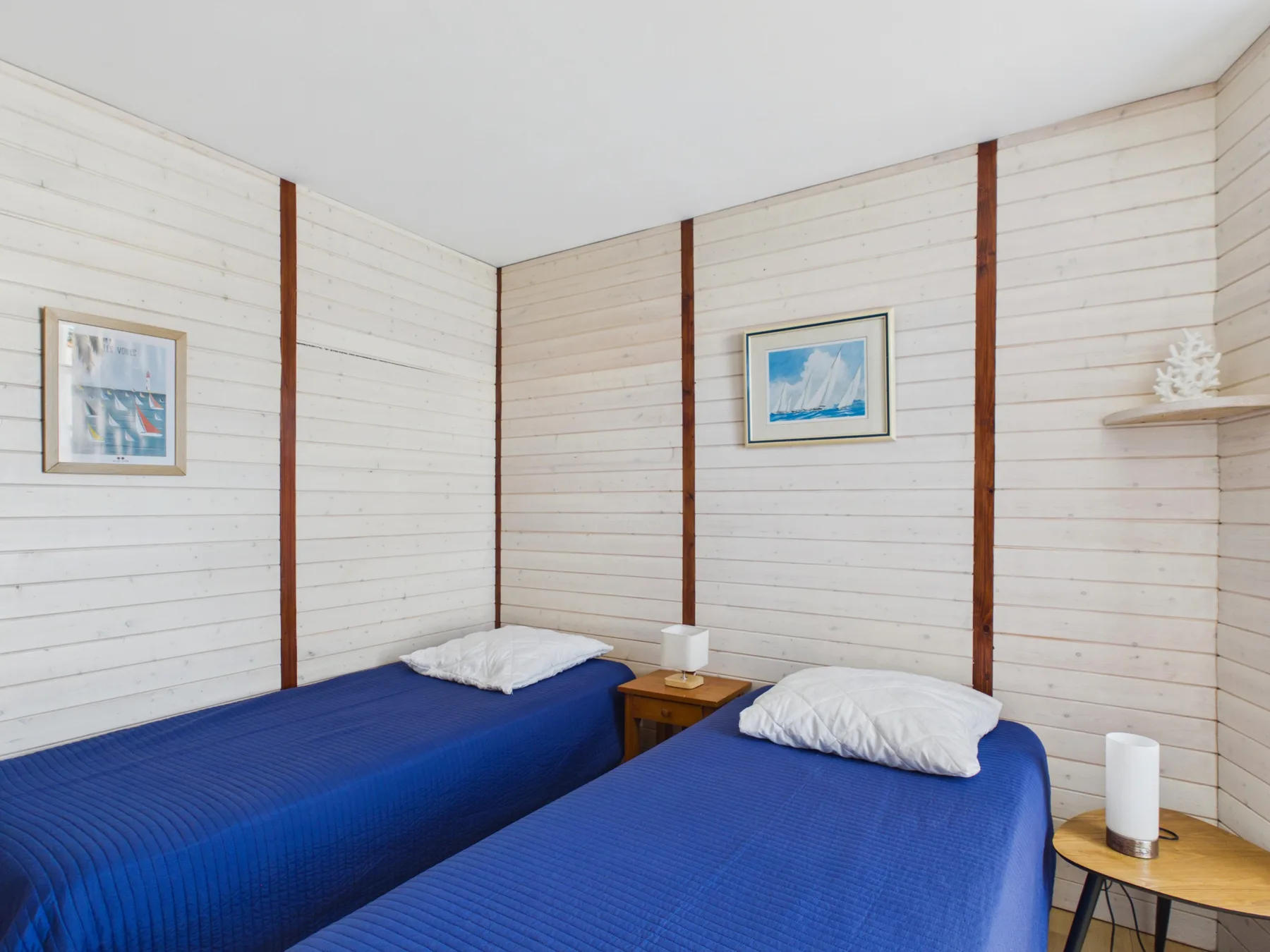 A bedroom with two beds covered in blue bedding.