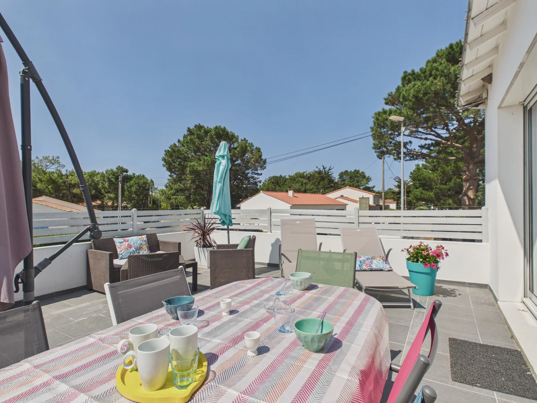 An outdoor dining area with a table and seating sits on a sunny terrace.