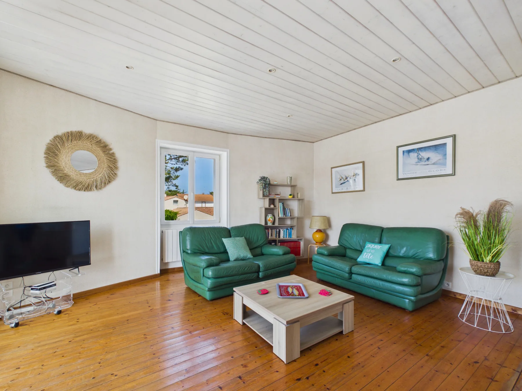 A living room with green seating, a coffee table, and a television.
