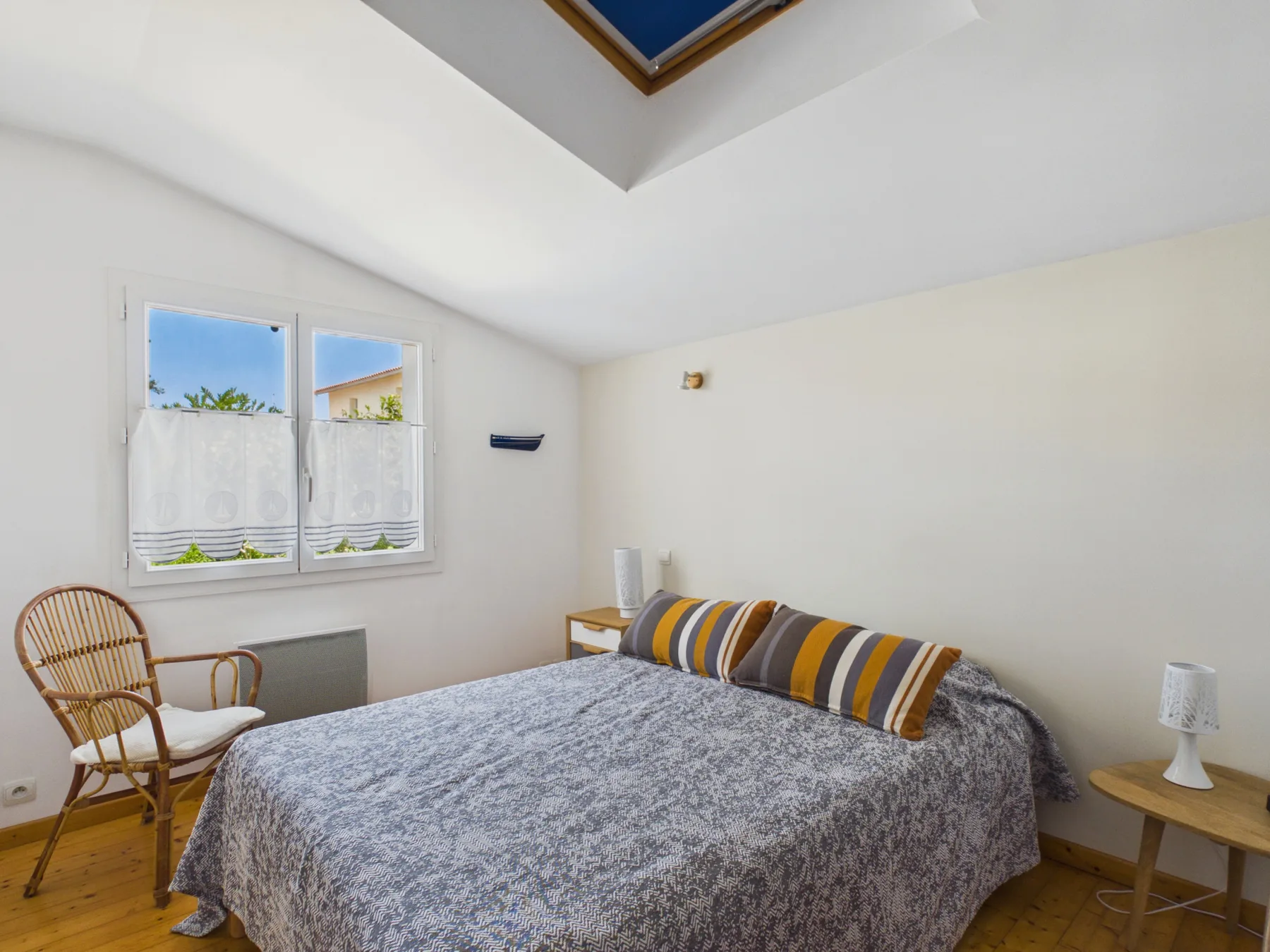 A bedroom with a bed, a window, and a skylight.