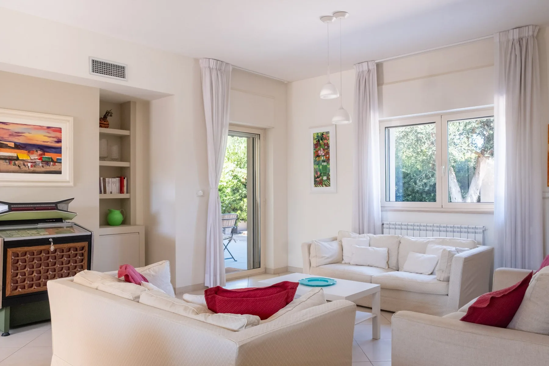 A bright living room with light-colored seating and large windows.