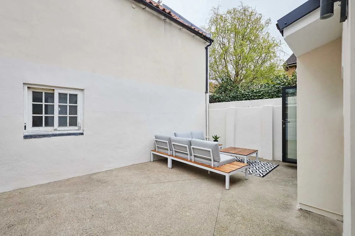 Un patio exterior con un banco largo y una mesa pequeña.