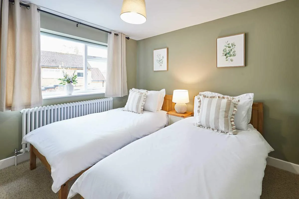 Dormitorio con dos camas junto a una ventana y un radiador.