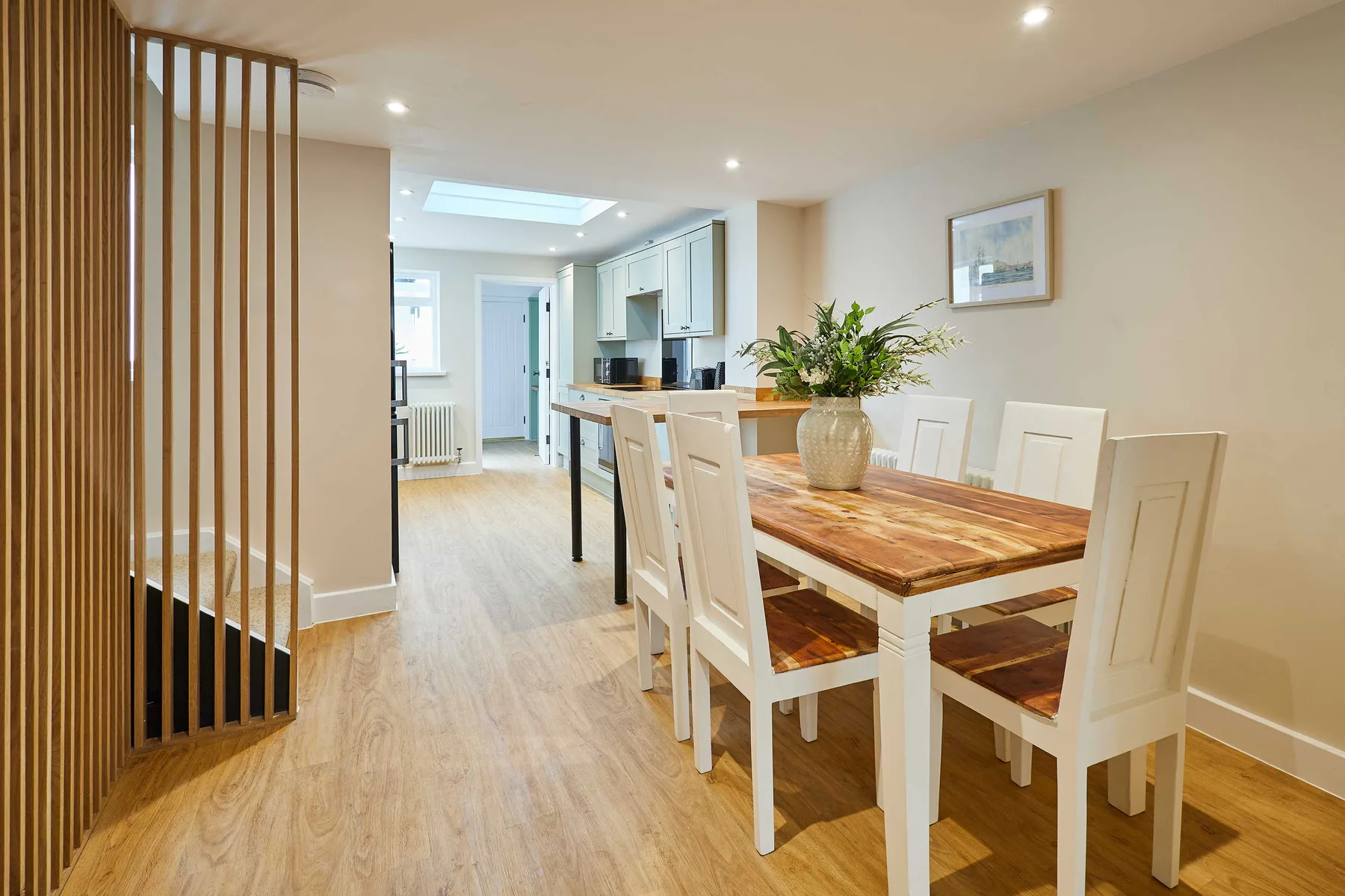 Un comedor abierto con una mesa de madera junto a una cocina luminosa.