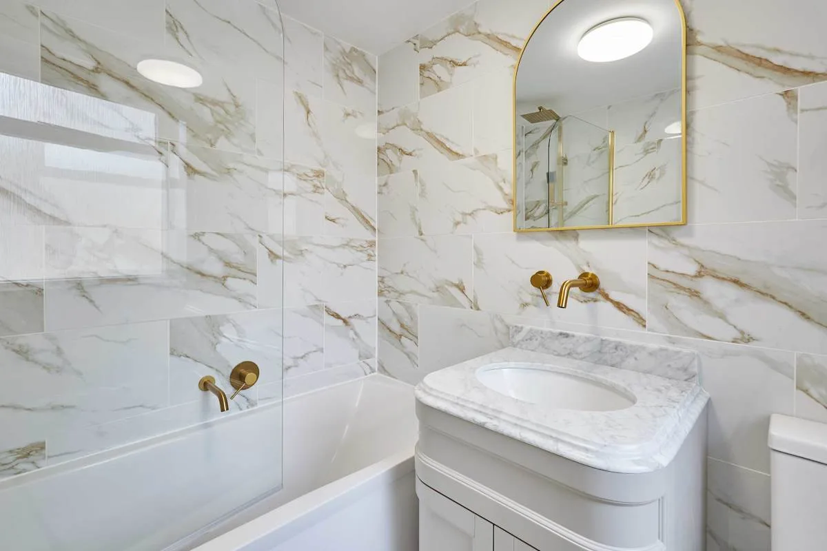 Un baño revestido de azulejos con bañera, lavabo y espejo de pared.