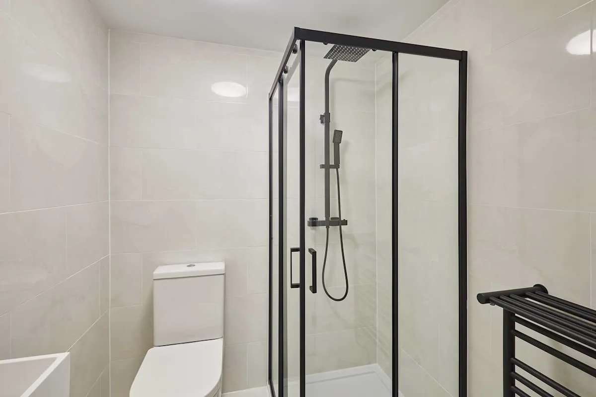 Un baño revestido de azulejos con una ducha de vidrio y un inodoro.