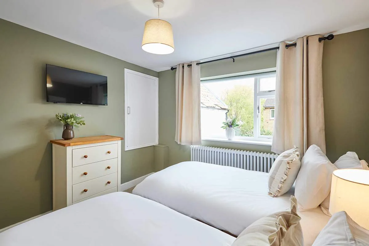 Un dormitorio con dos camas, una cómoda y una ventana con cortinas.