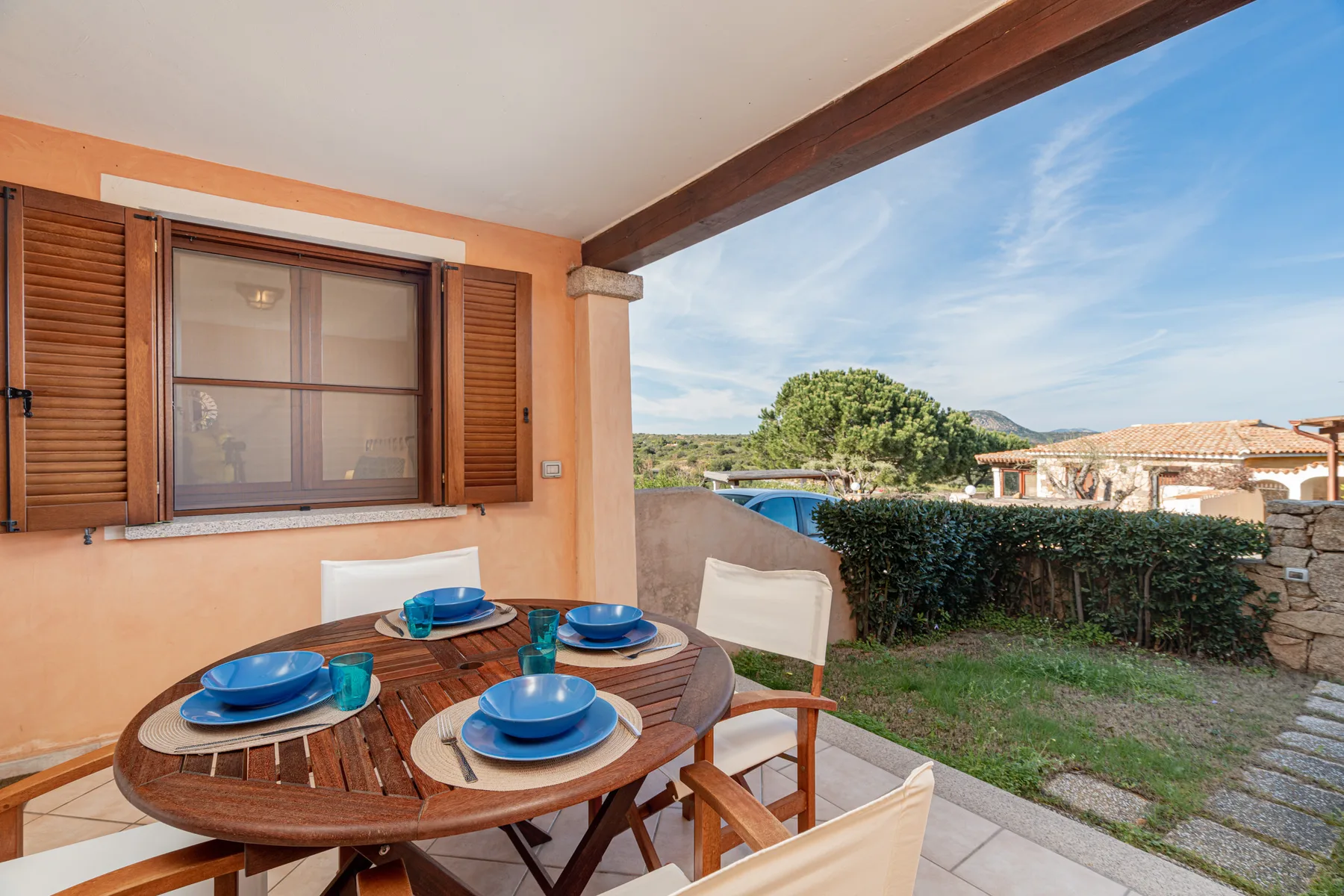 A covered outdoor dining area with a wooden table and garden view.
