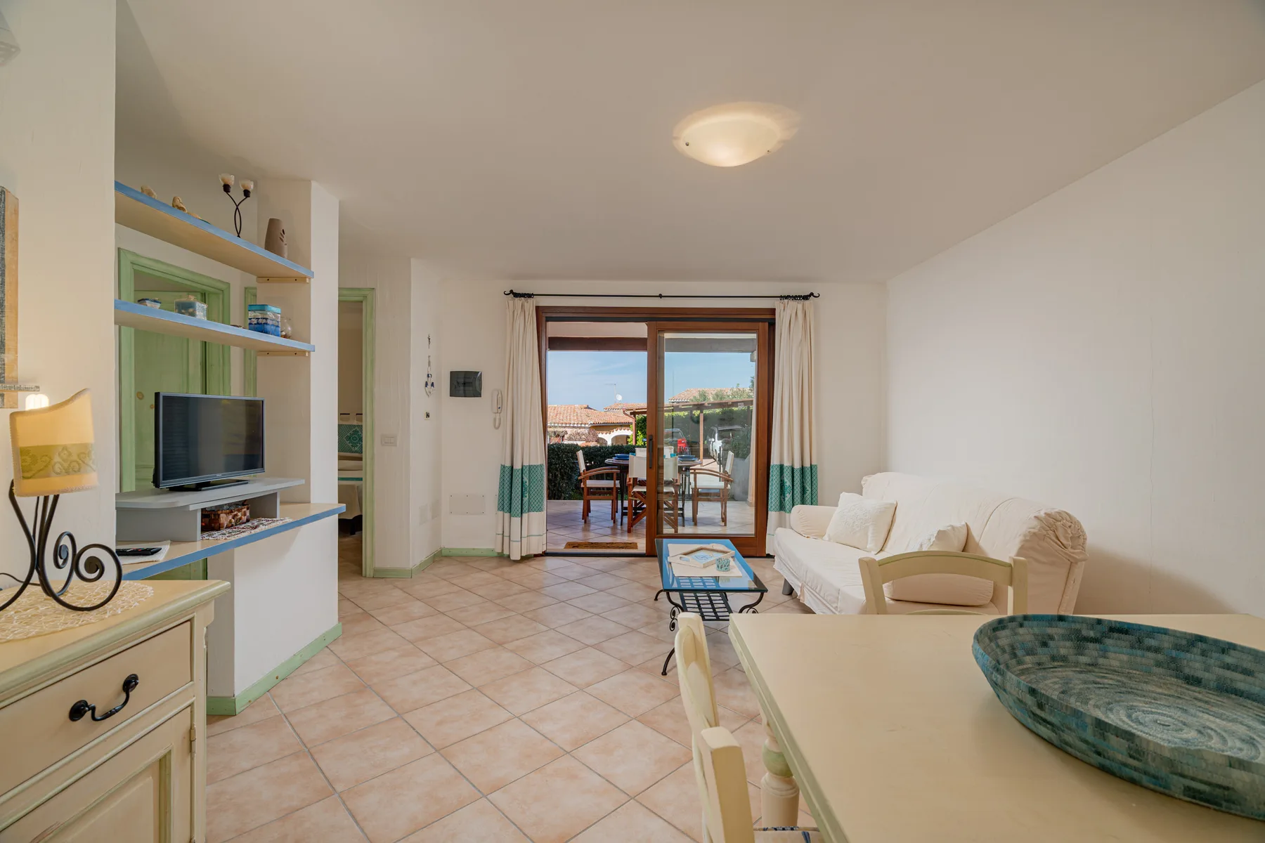 A bright living room opens onto a balcony through glass doors.