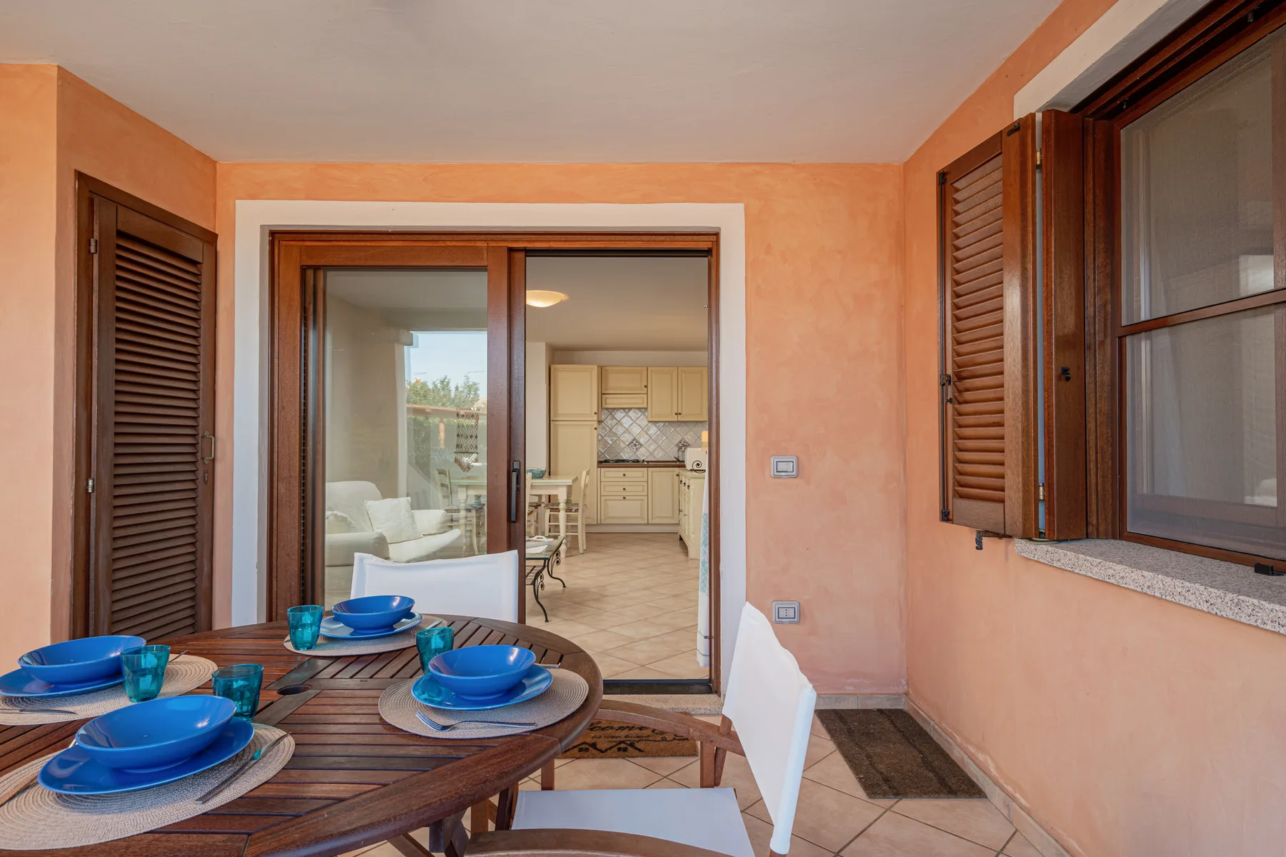 A covered patio with a dining table and view into a kitchen.