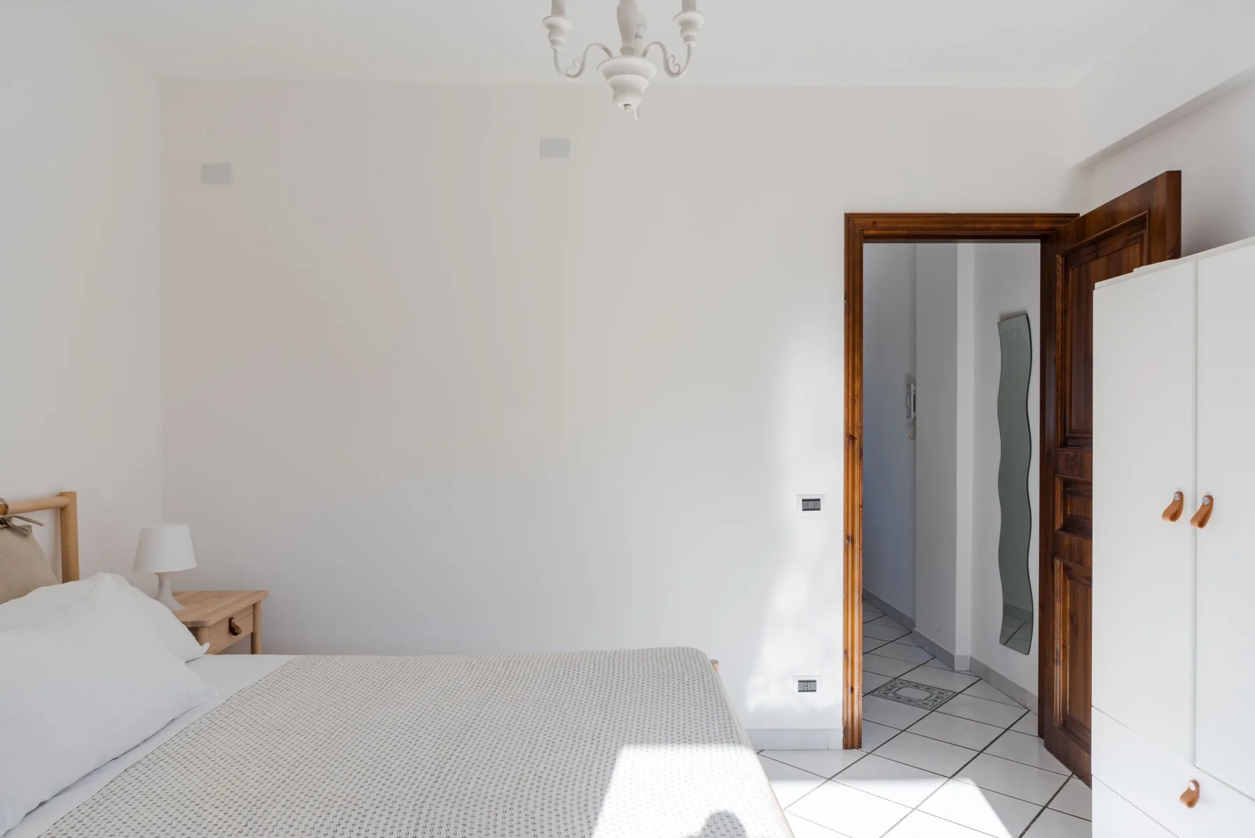 Un dormitorio con una cama junto a una puerta abierta y un armario.
