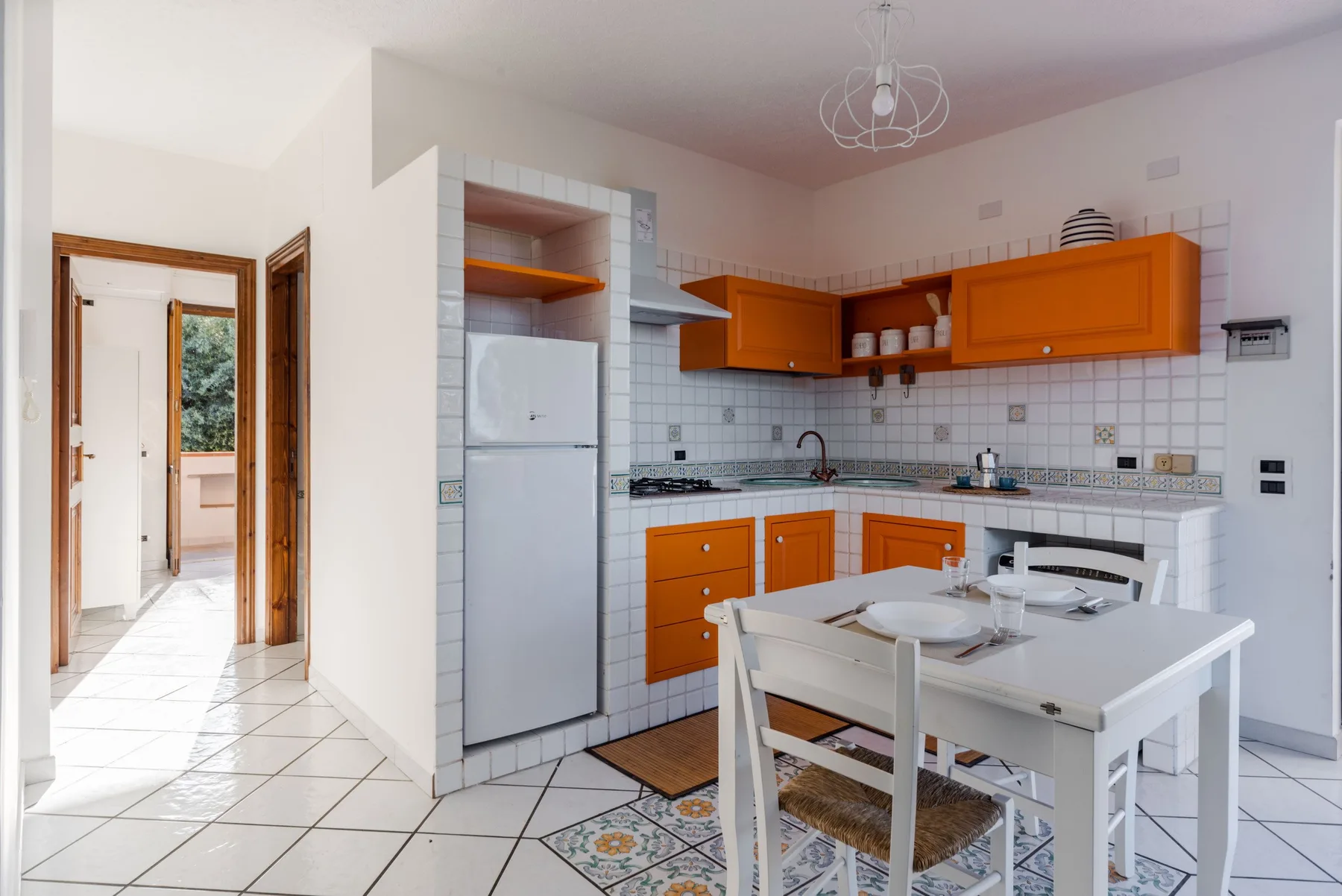 Una cocina y comedor con armarios naranjas y una mesa blanca.