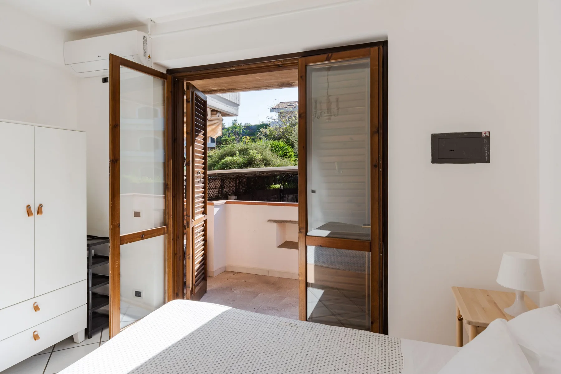 Un dormitorio luminoso se abre a un pequeño balcón por unas puertas de cristal.