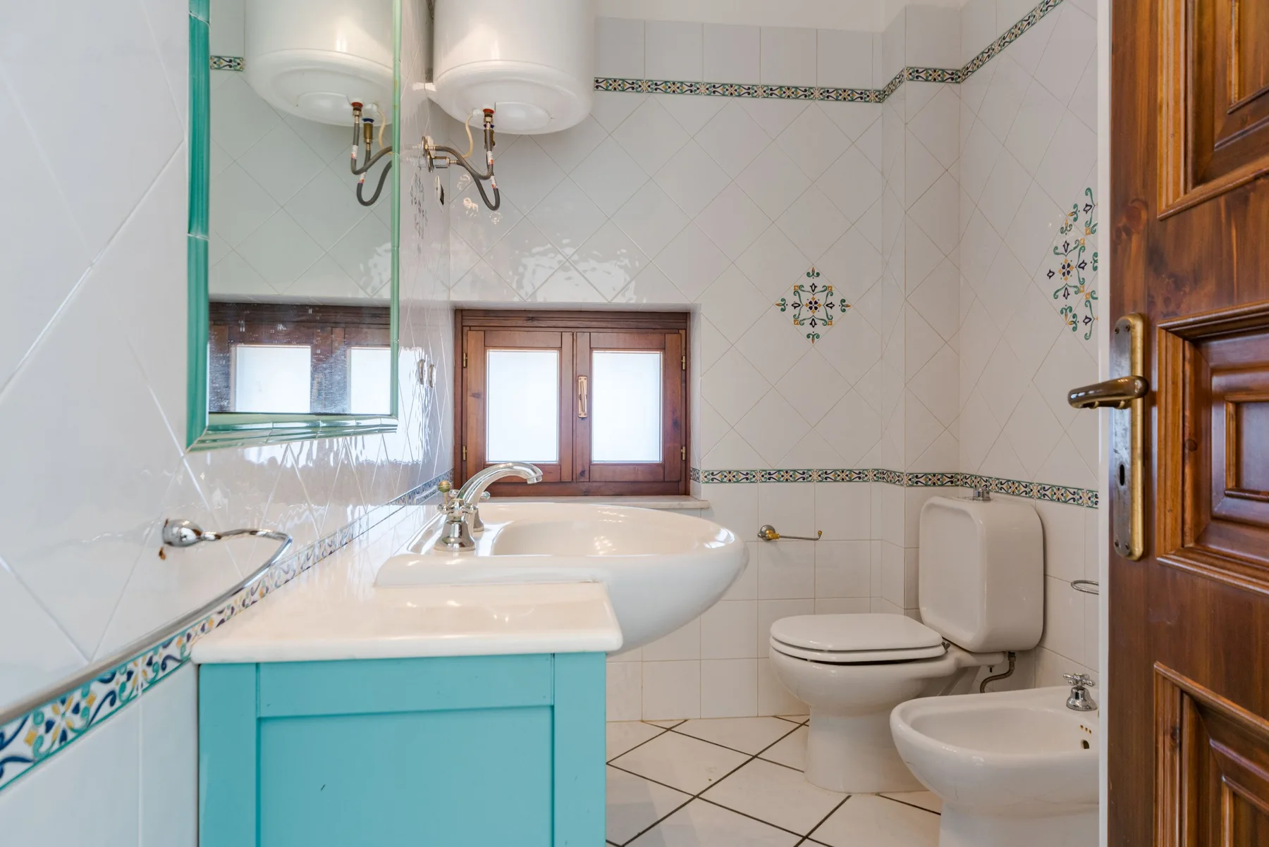 Un baño con azulejos, lavabo, inodoro y bidé.