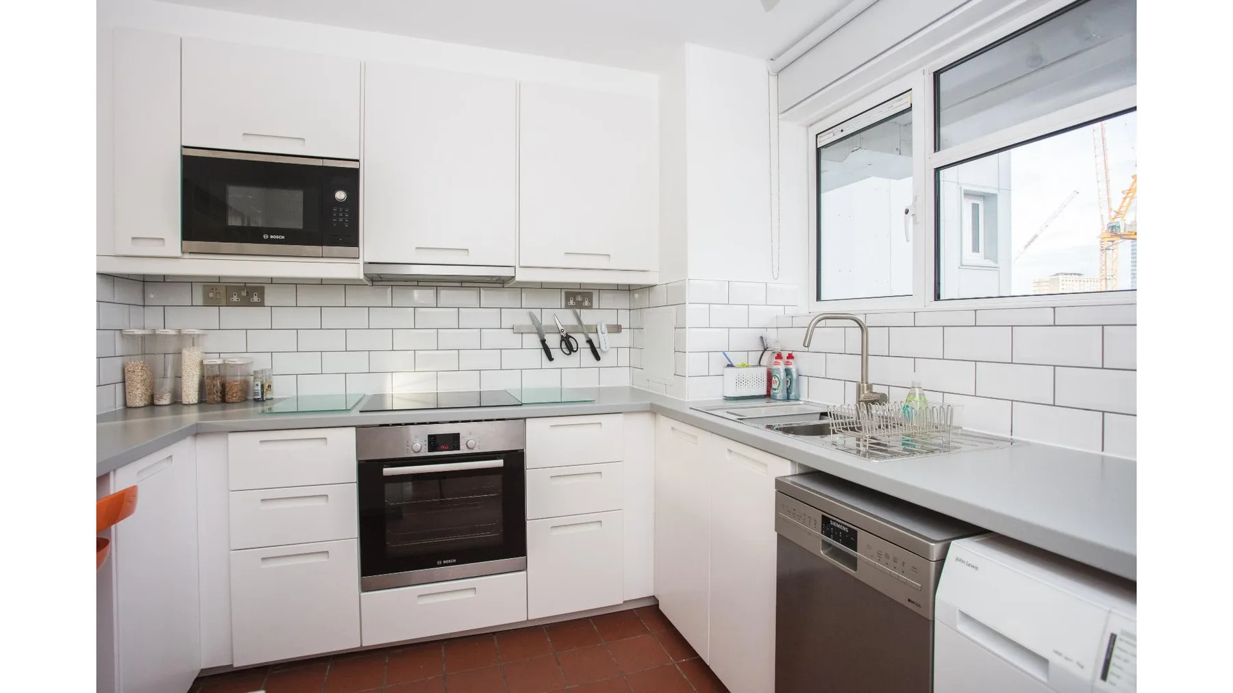 A bright white kitchen with a tiled backsplash and large windows.