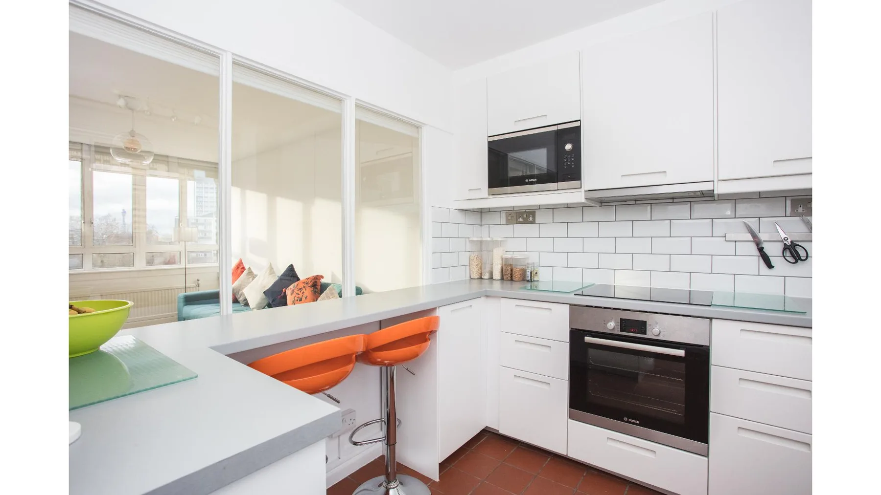 A bright white kitchen with a counter, cooktop, and built-in oven.