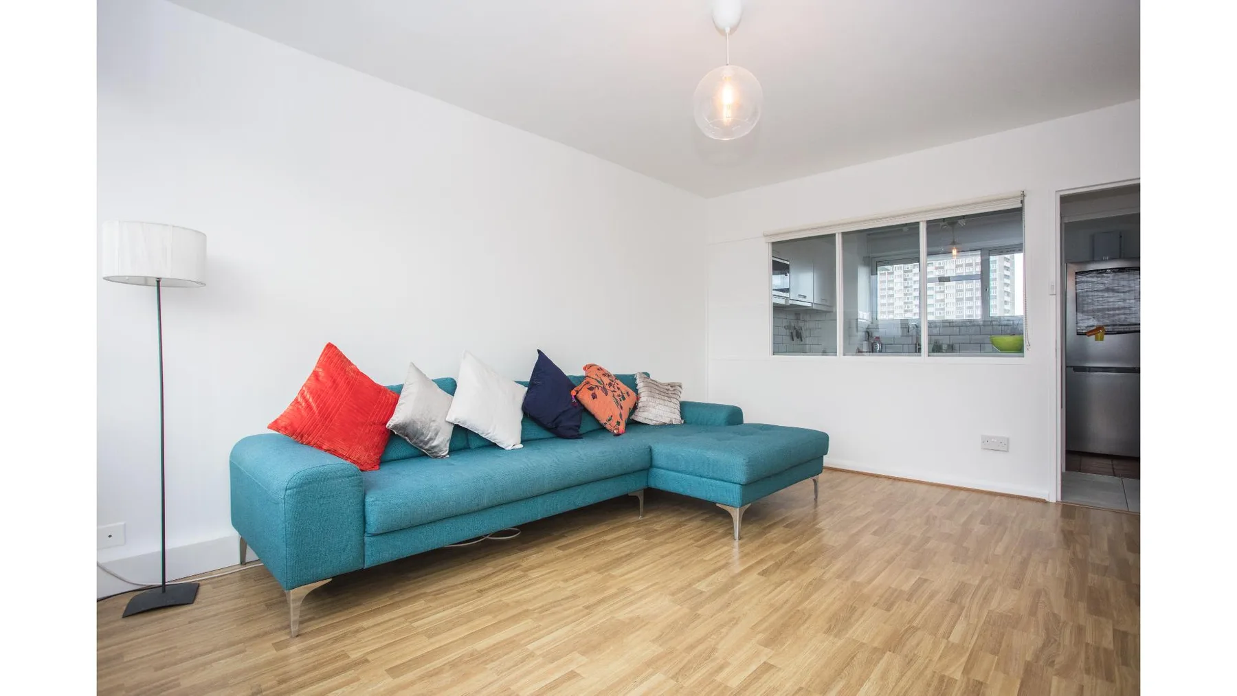 A bright living room with a turquoise sectional and windows.