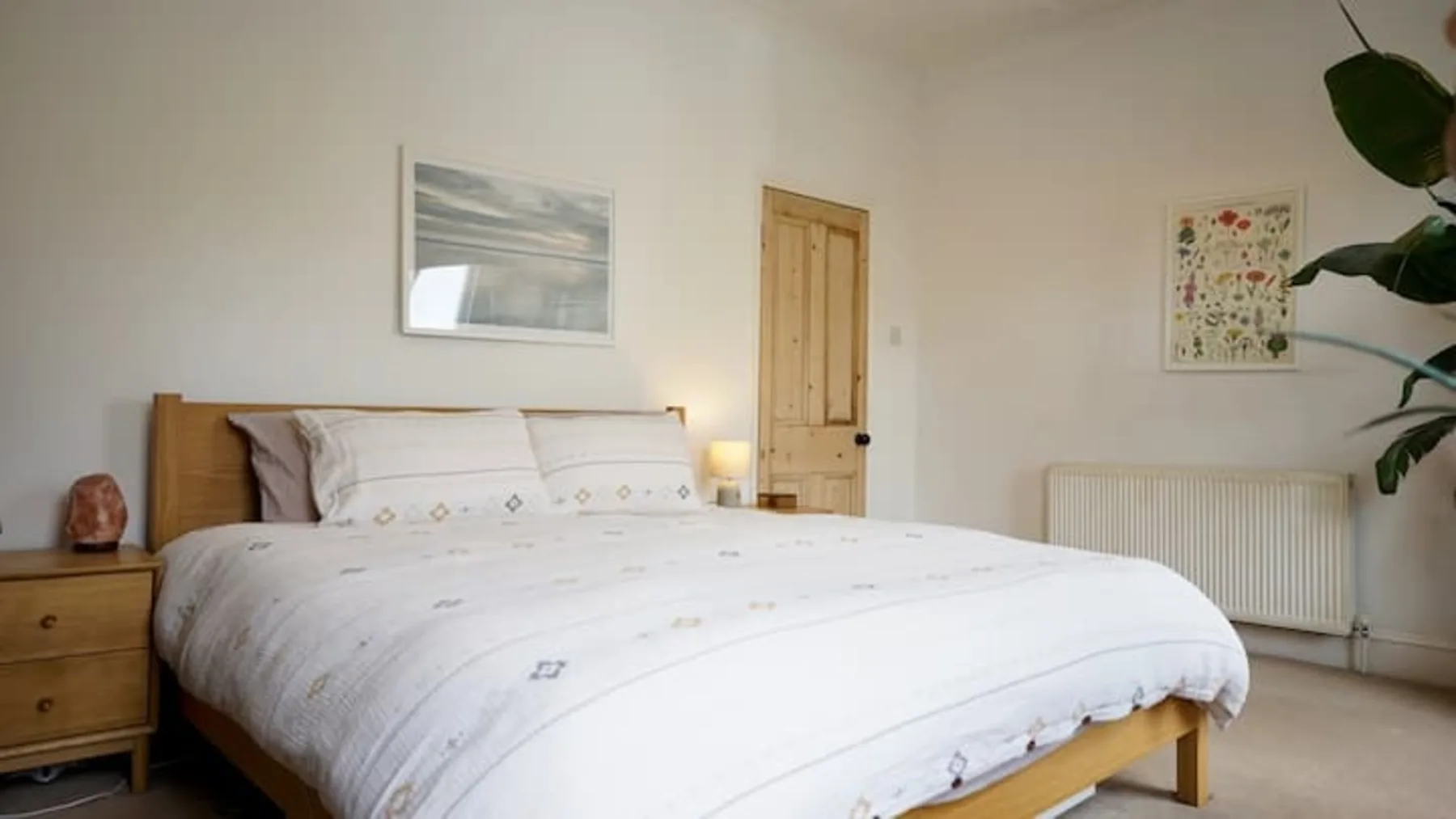 A bedroom with a neatly made bed and a wooden door.