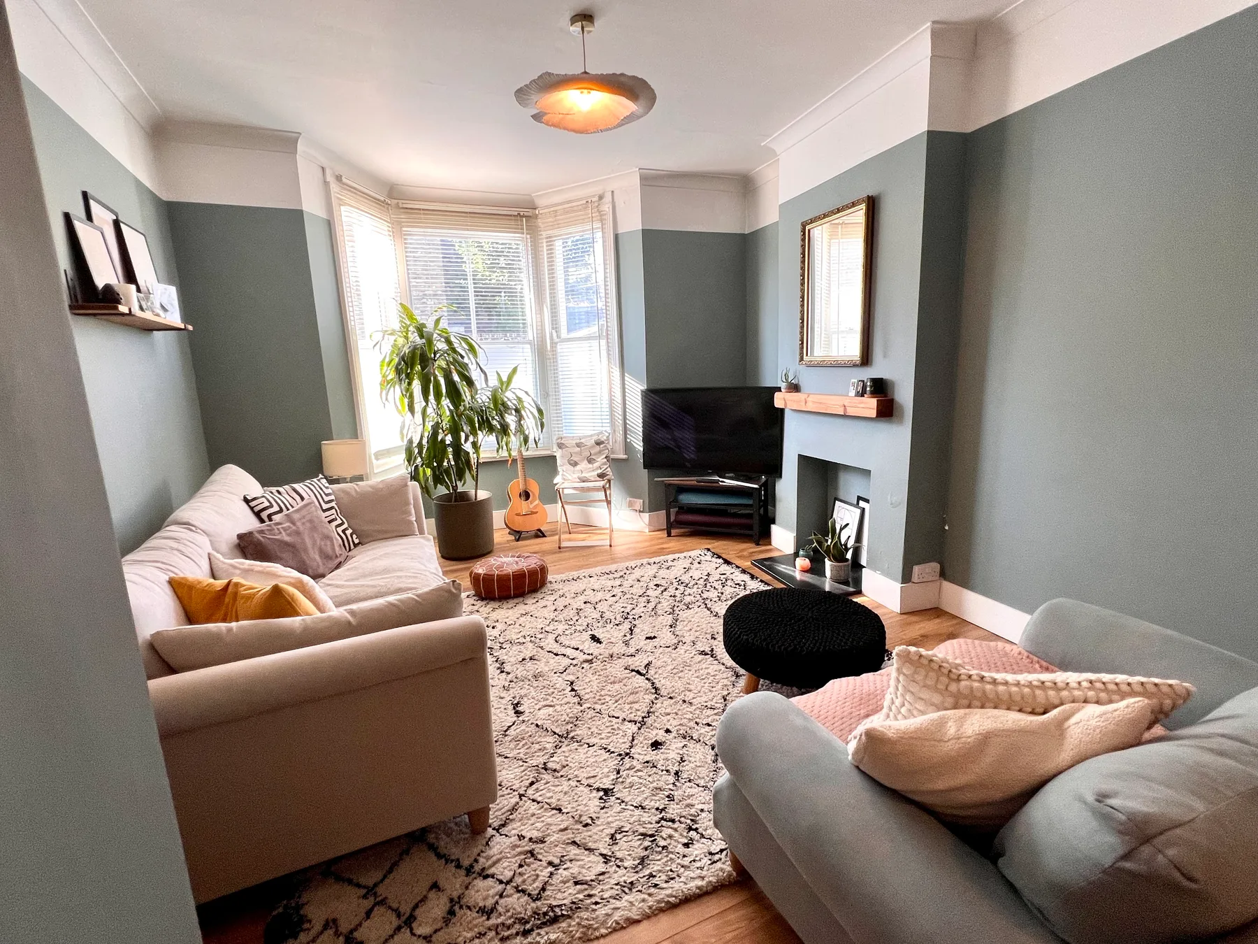 A living room with seating, a patterned rug, and a bay window.