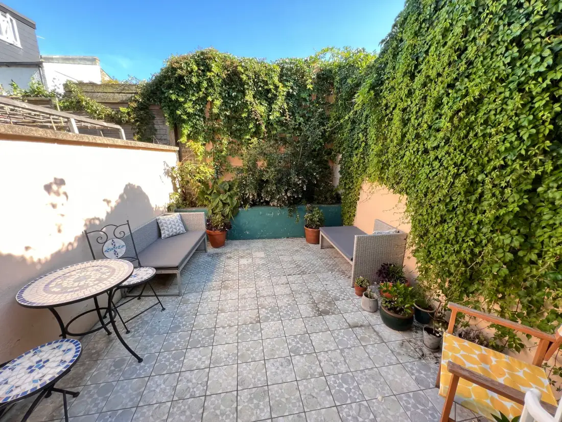An outdoor patio with seating and leafy greenery along the walls.