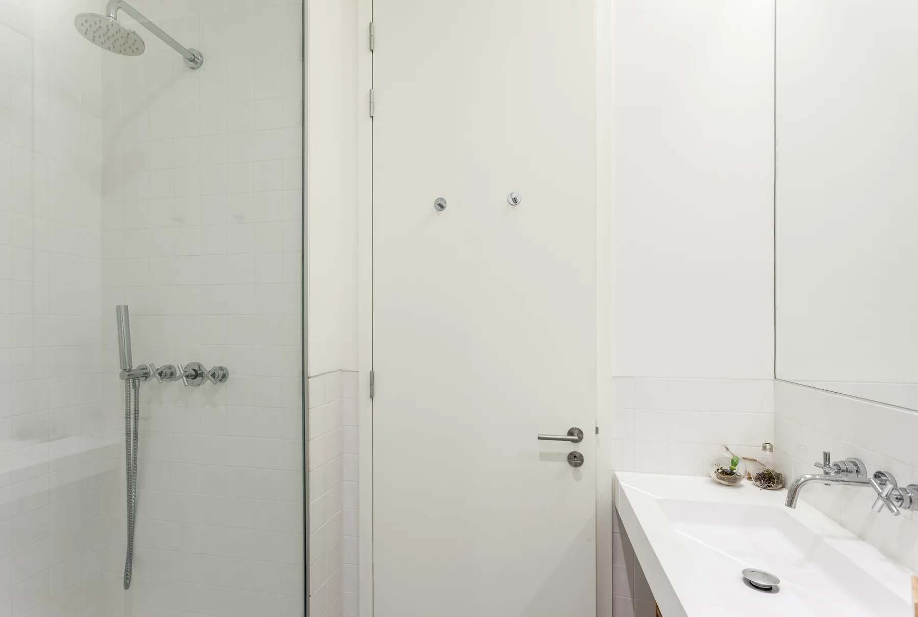 A bright bathroom with a shower and a white sink.