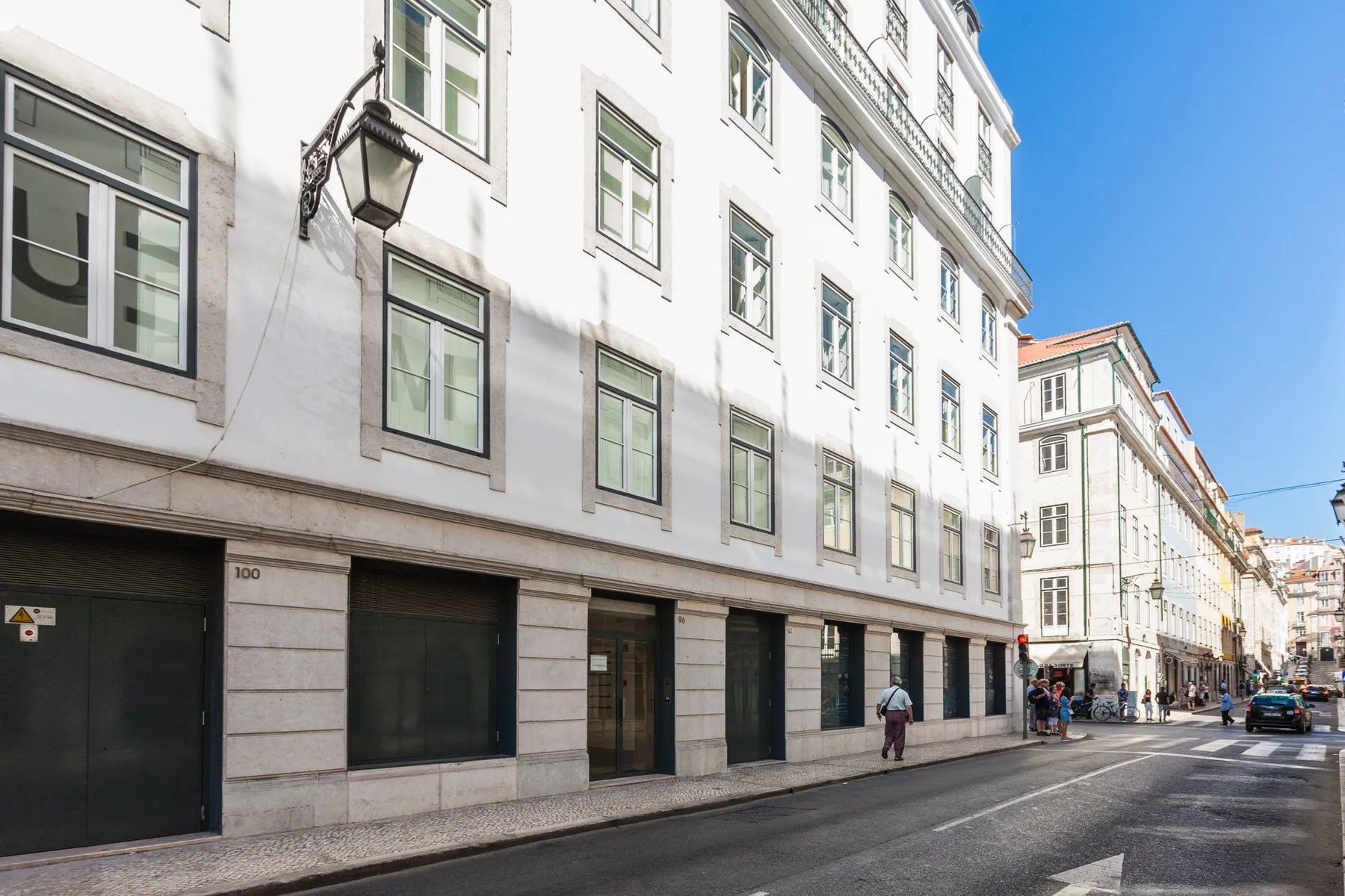 A city street lined with tall white buildings and ground-floor storefronts.