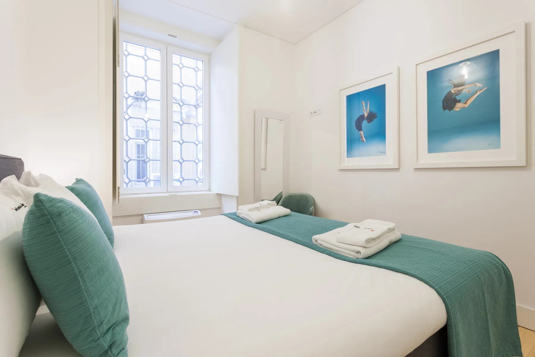 A bedroom with a neatly made bed and framed artwork on the wall.