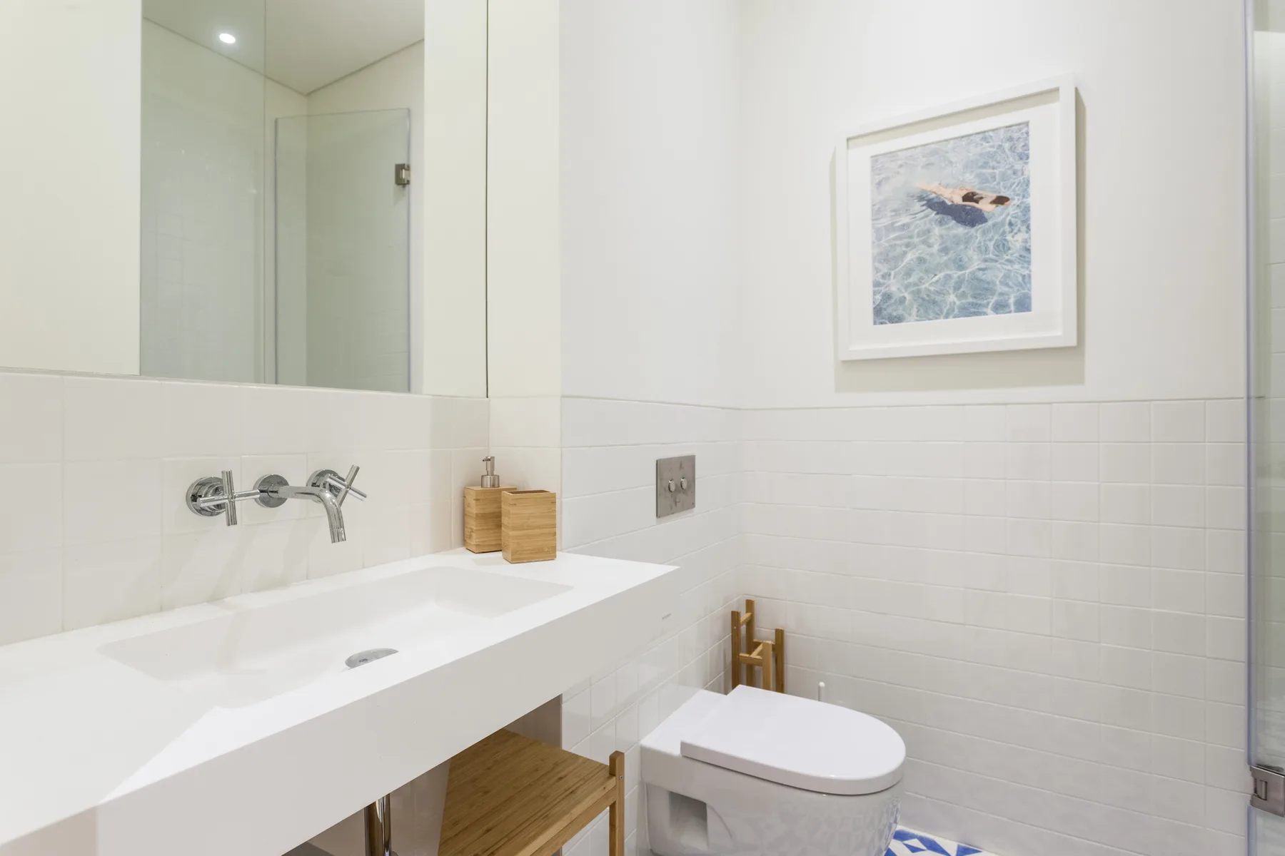 A bright bathroom with a white sink, toilet, and framed wall art.