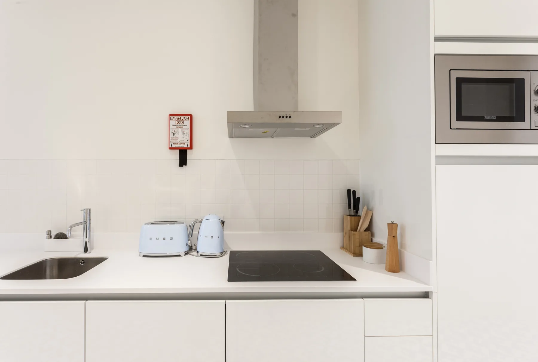 A bright kitchen counter with a sink, cooktop, and small appliances.