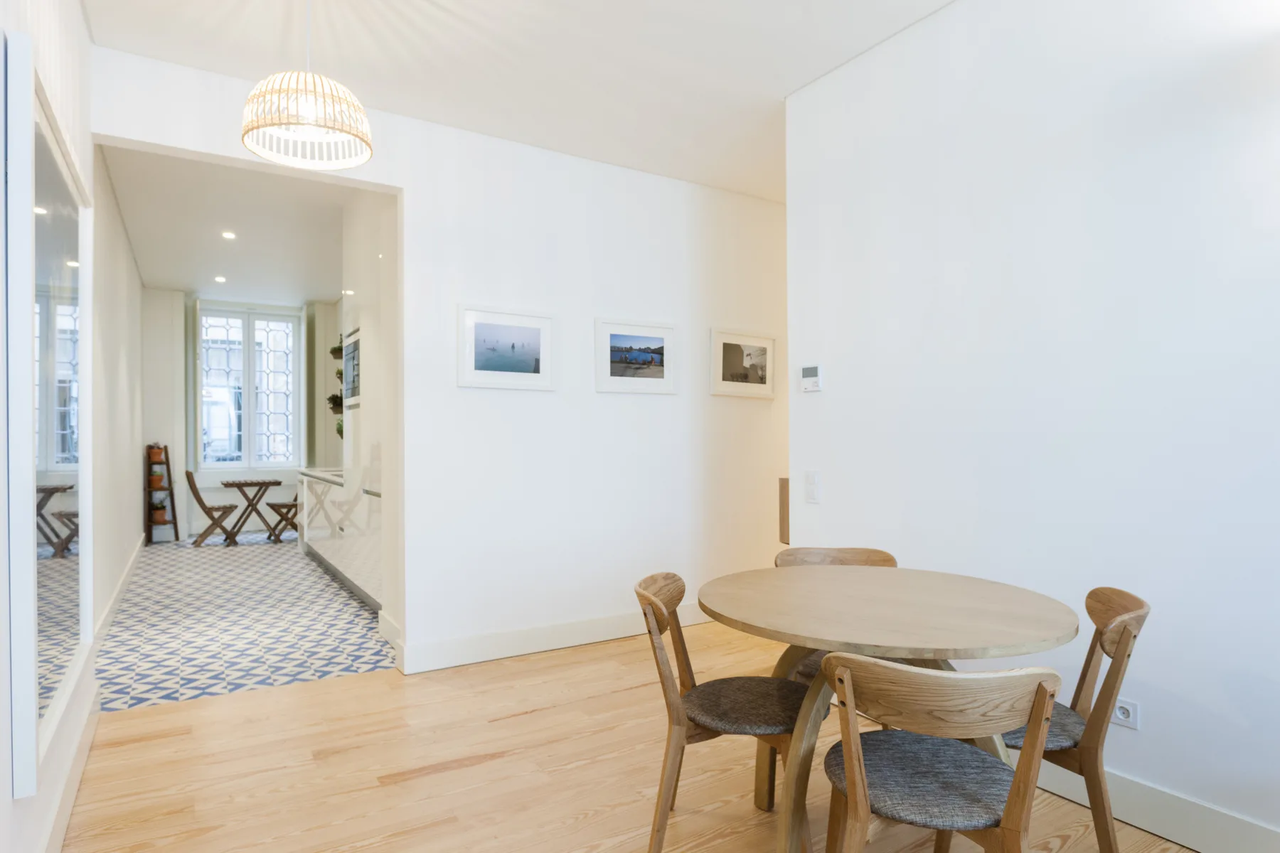 A dining area with a round table and chairs beside a bright hallway.