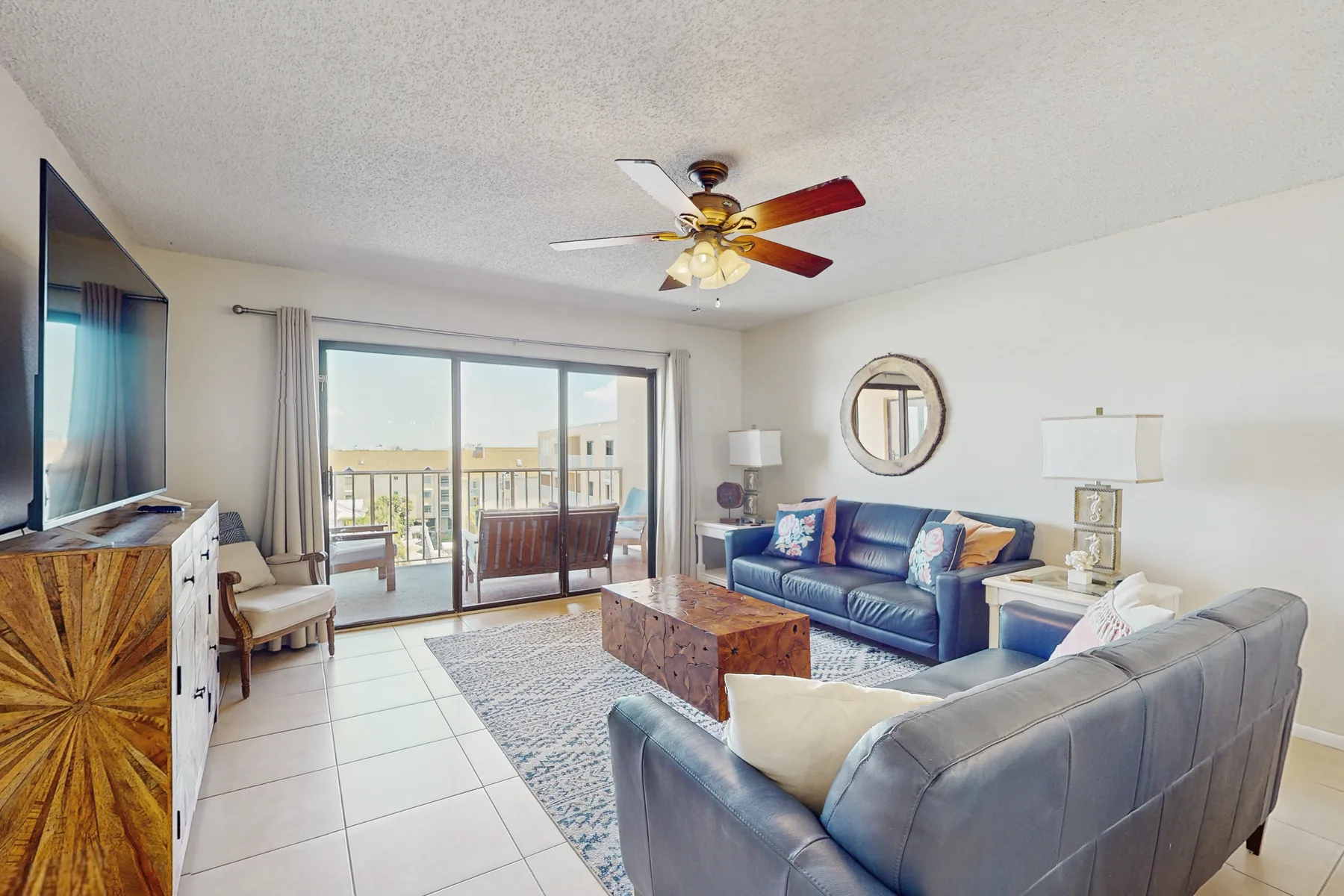 A bright living room with seating arranged around a coffee table beside sliding glass doors.