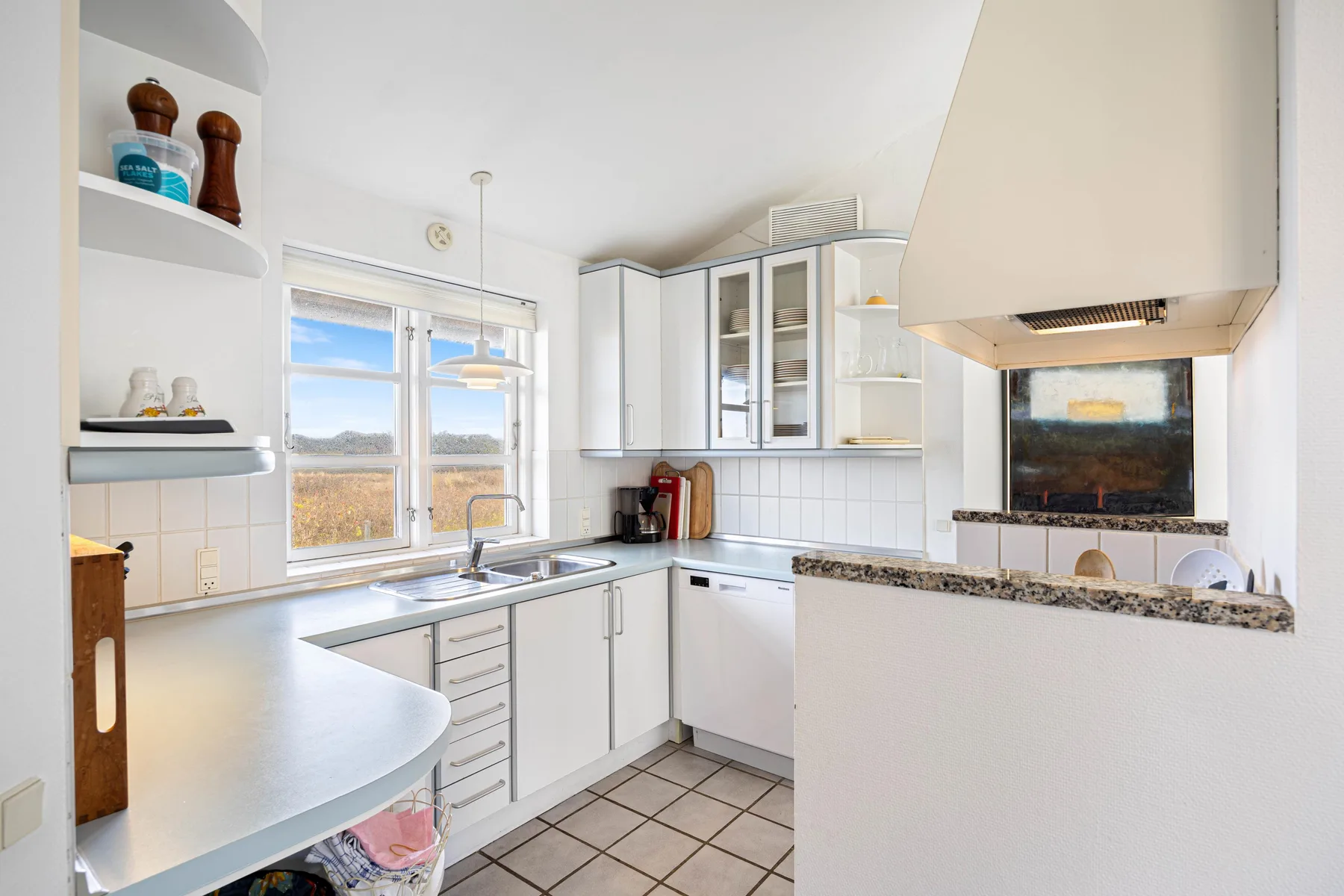 Una cocina luminosa con armarios blancos, una ventana y una superficie de trabajo central.