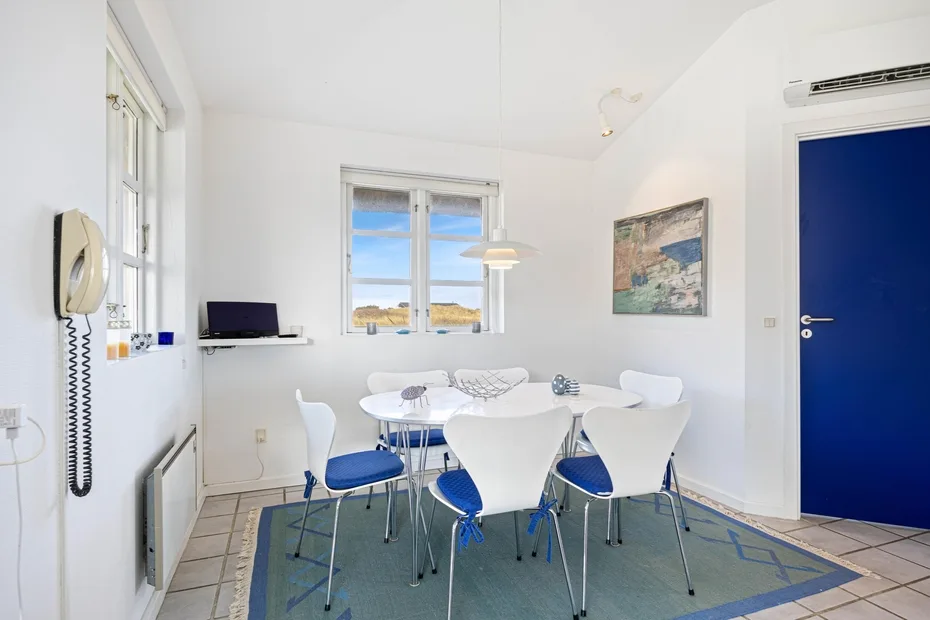 Un comedor luminoso con asientos blancos alrededor de una mesa y una ventana.