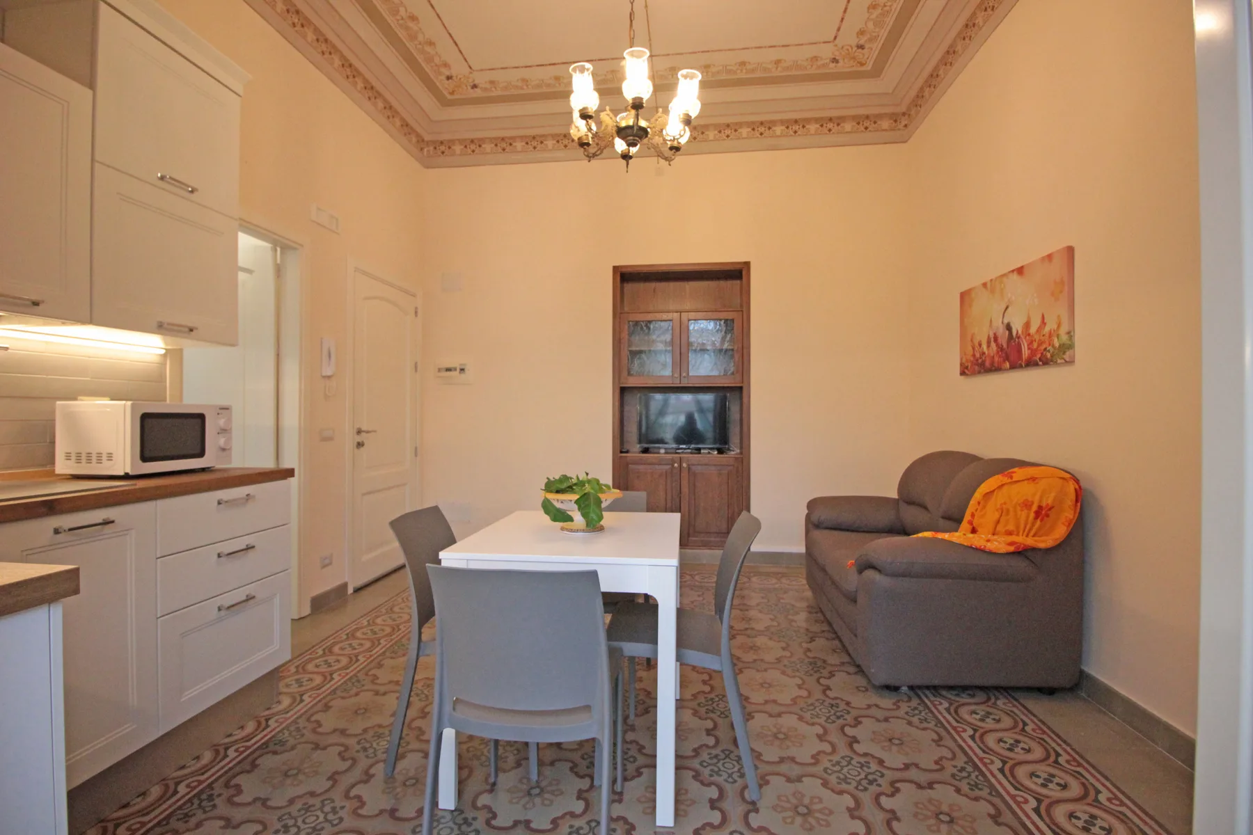 A dining and living area with a white table and gray seating.