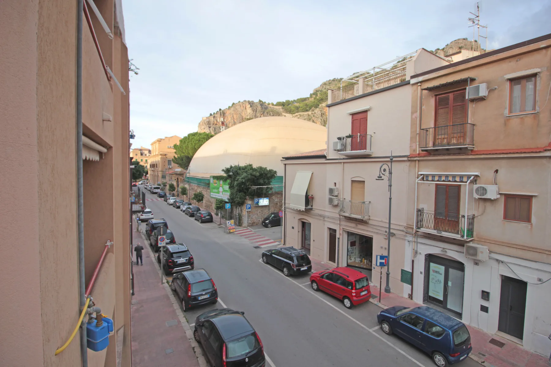 A town street lined with low-rise buildings and parked cars.