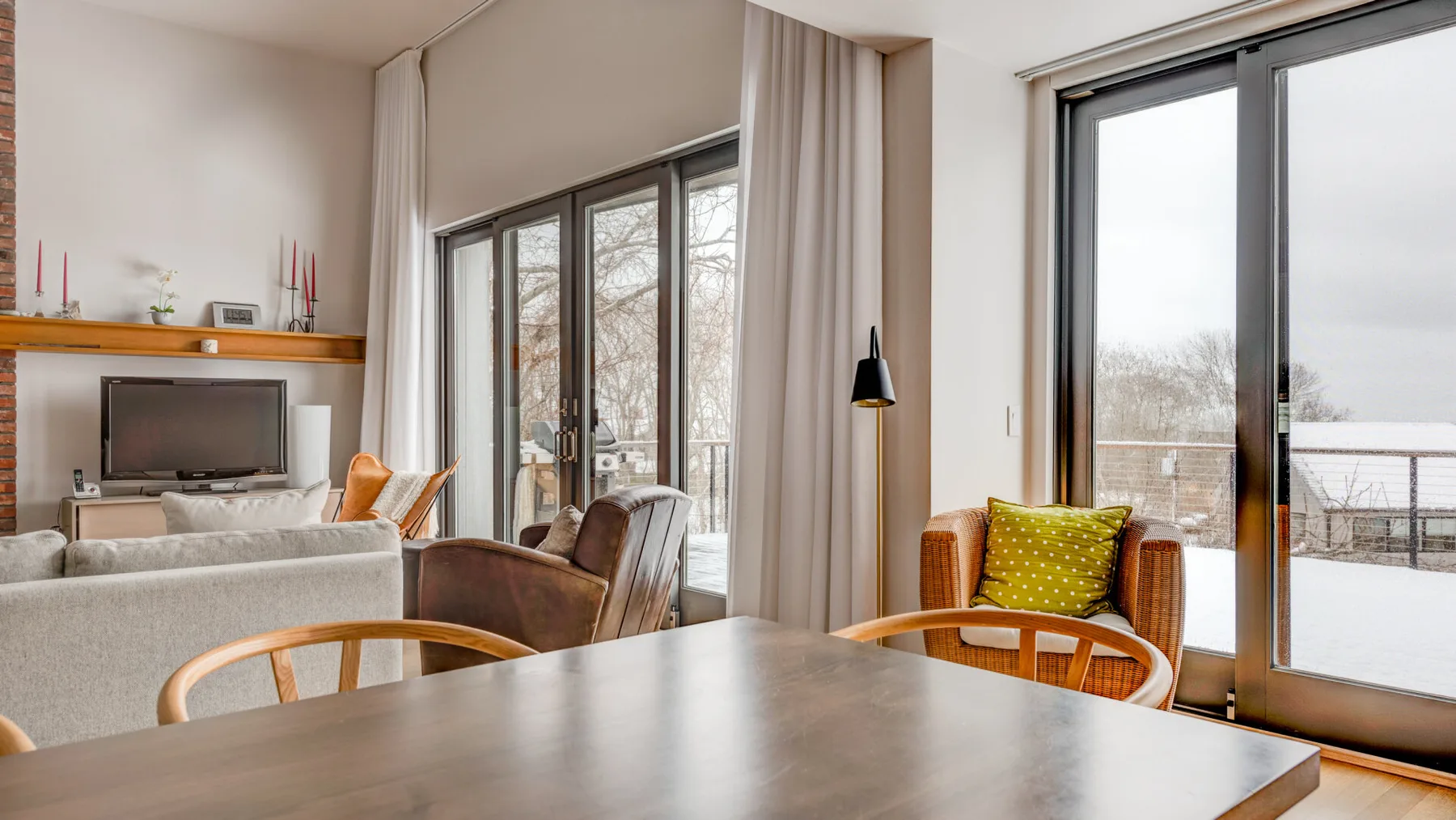 A bright living room with seating beside large windows and a glass door.