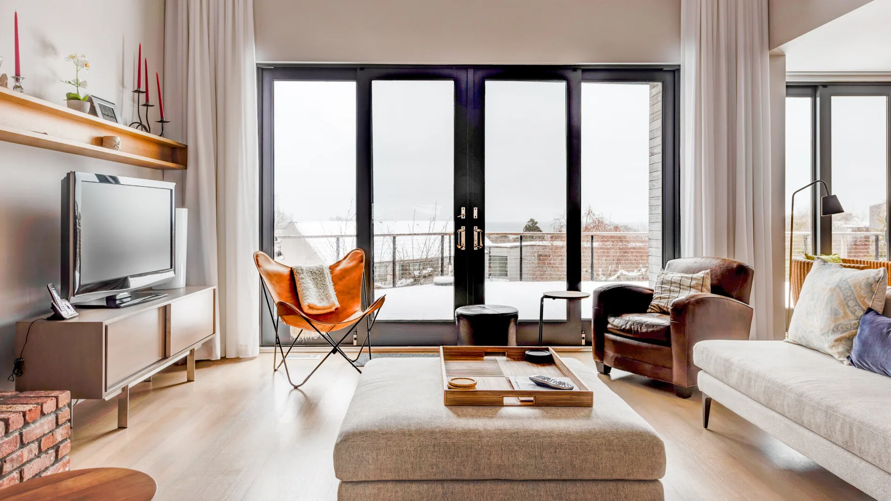 A bright living room with a large window, a television, and seating.