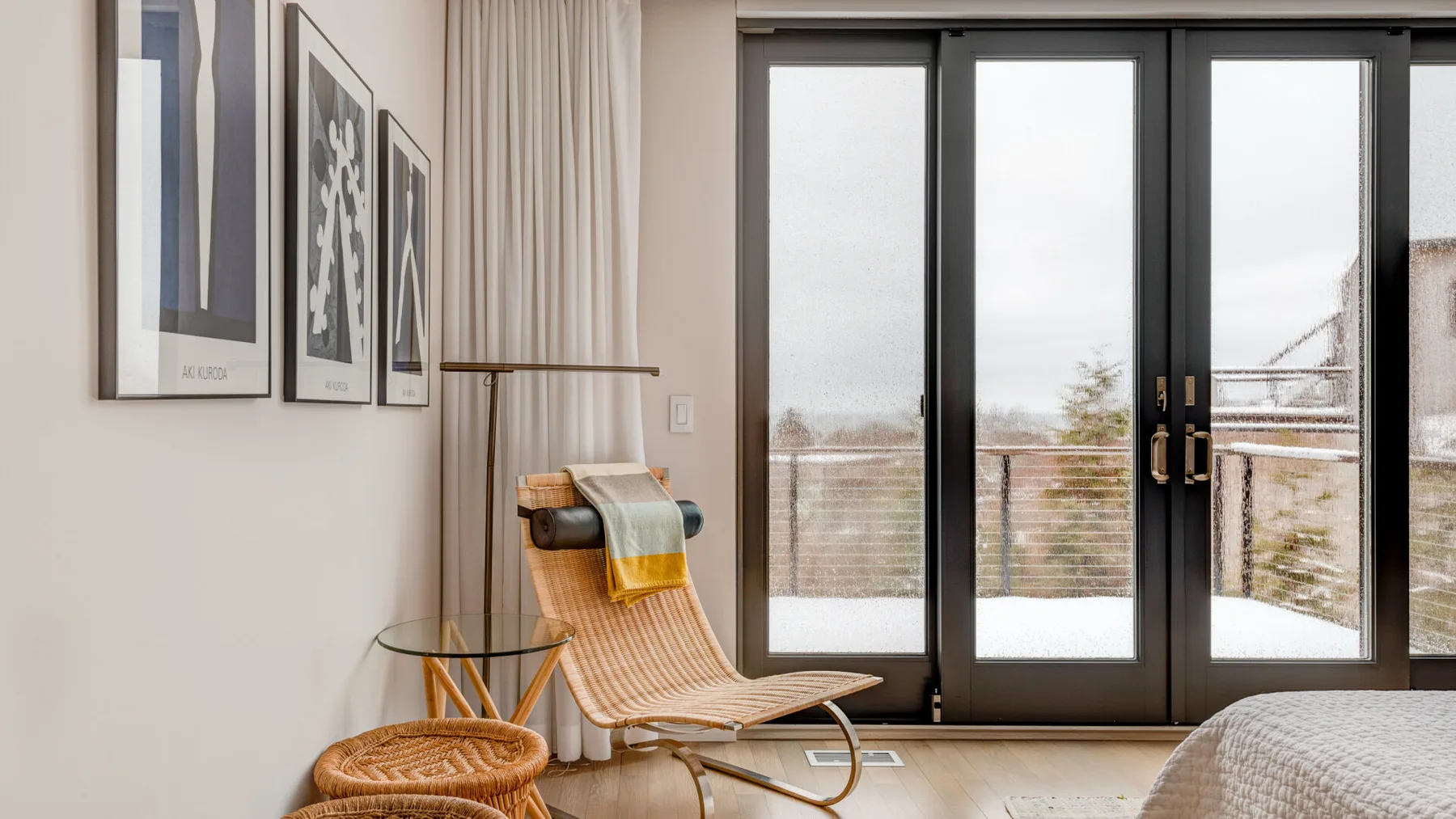 A bright sitting area with a woven lounge chair beside large glass doors.